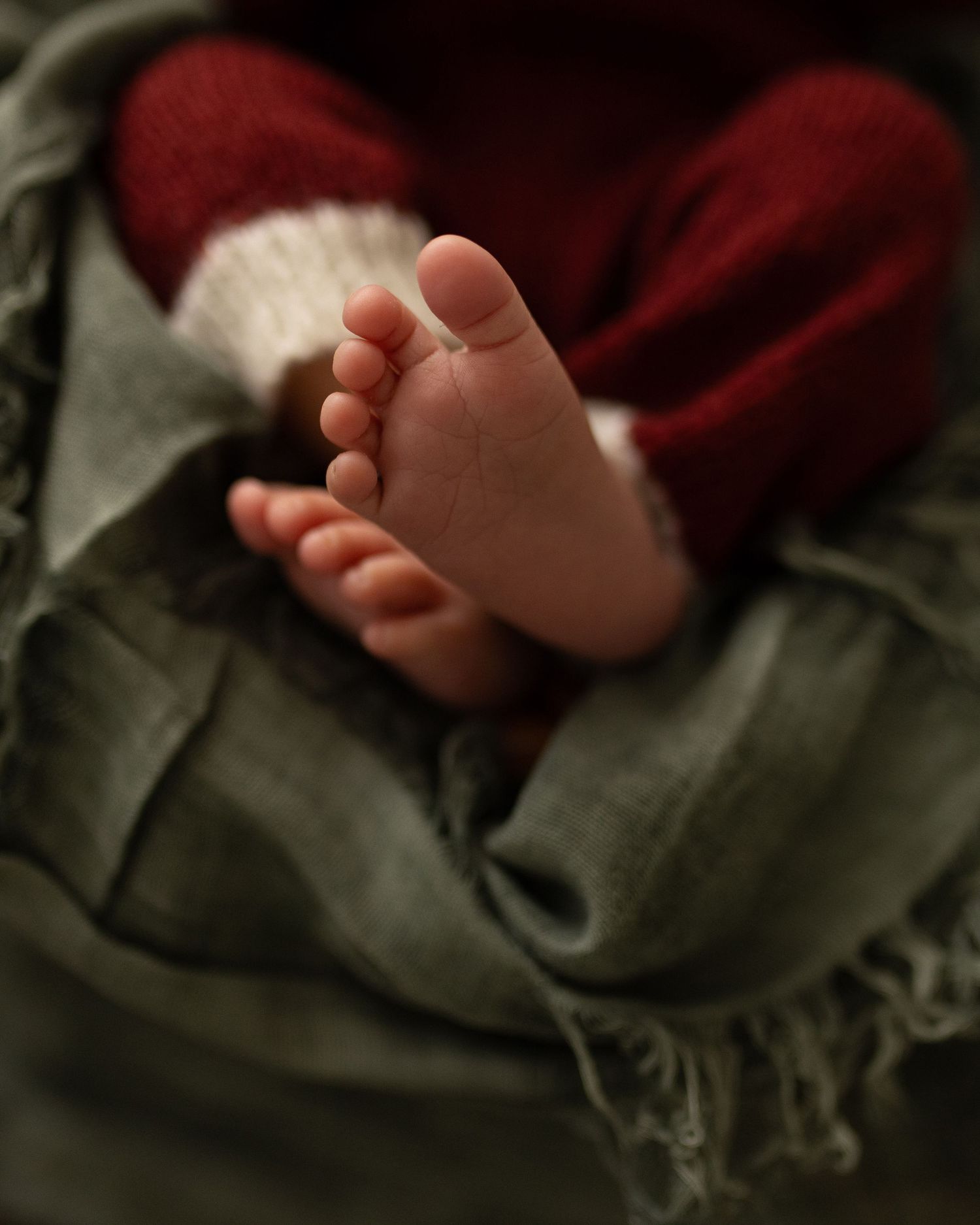 A series of close-up photos showing tiny baby feet against a red and gray blanket background.