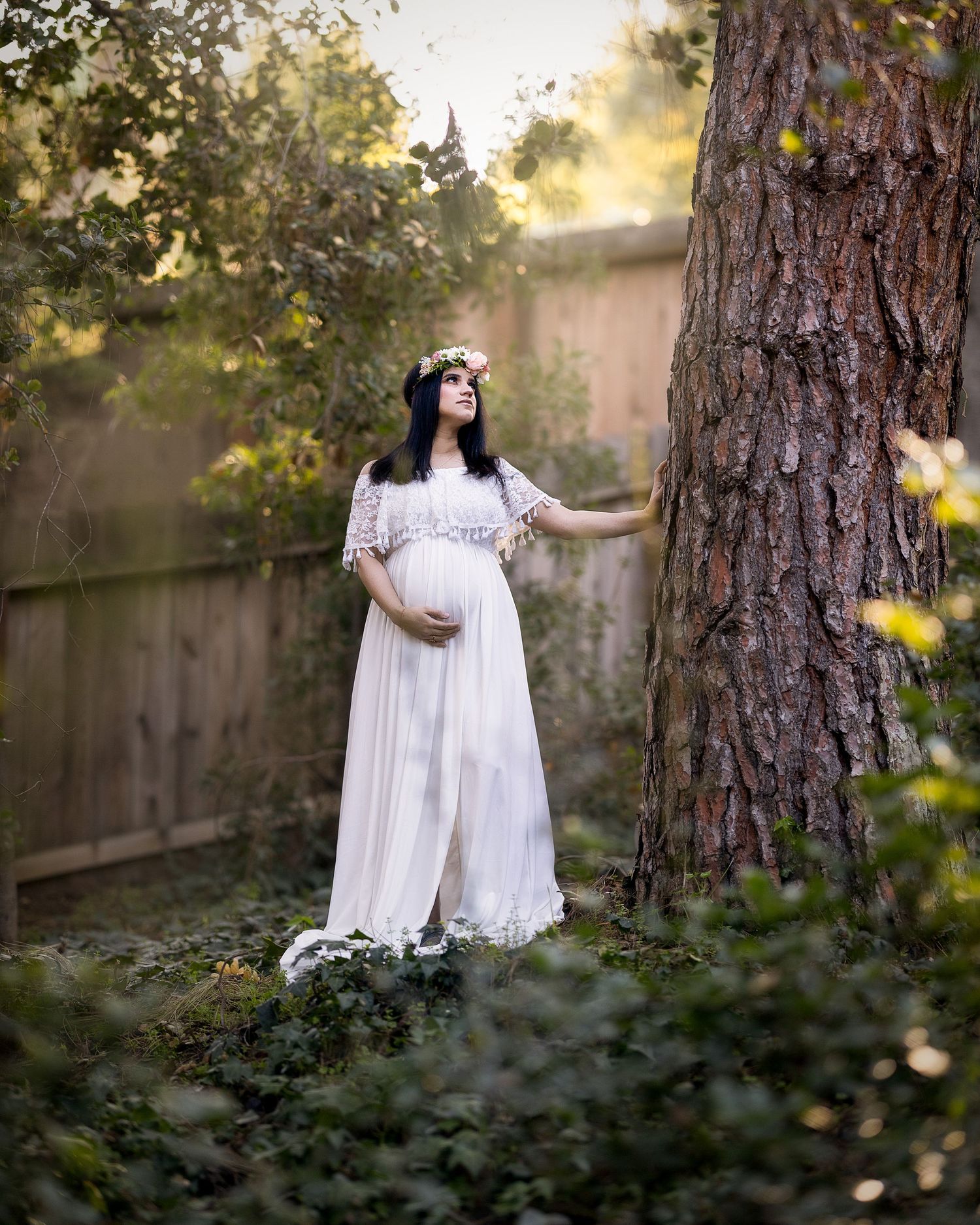 A dreamy outdoor portrait session in a wooded setting with soft golden light filtering through the trees.