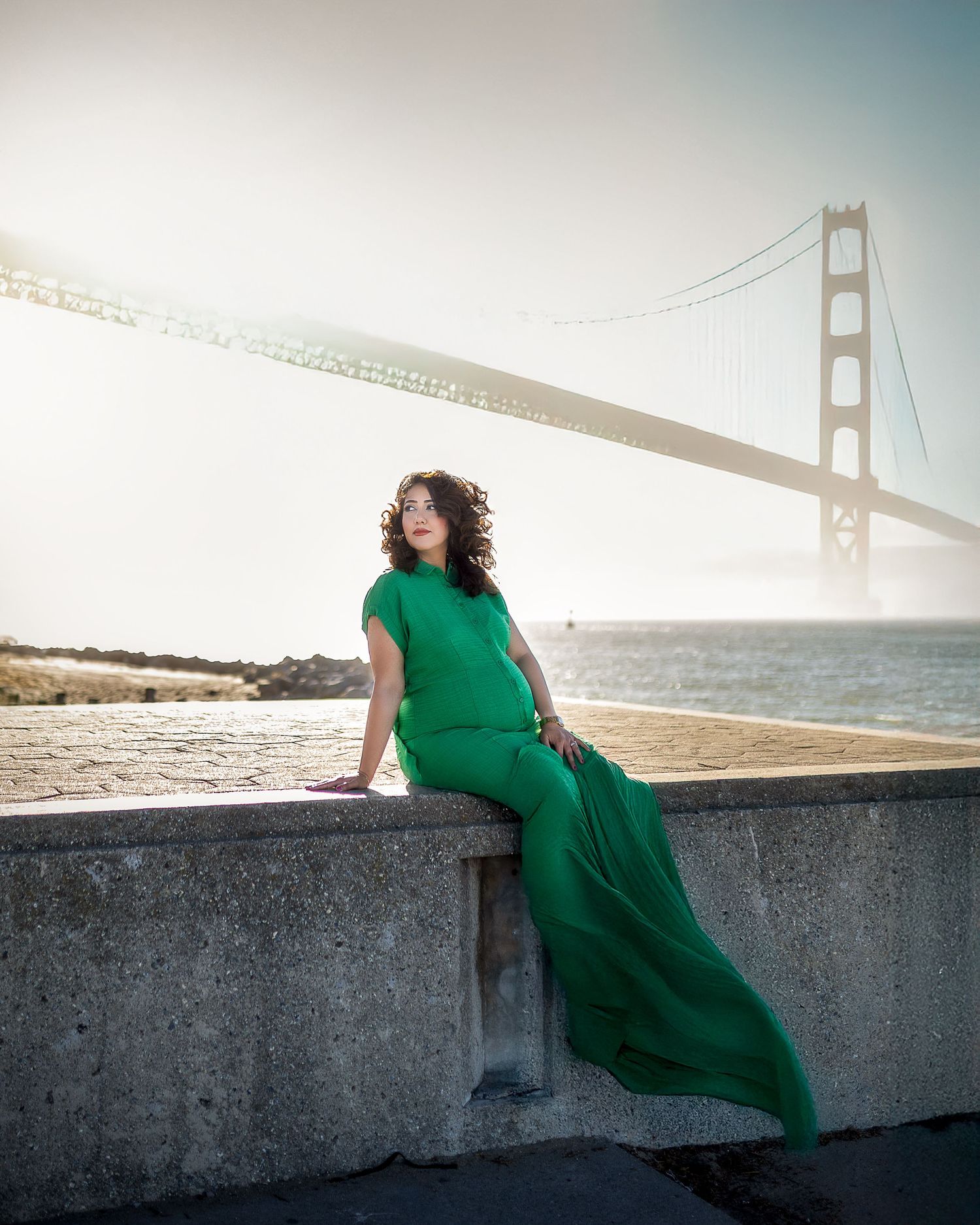 A flowing emerald green dress catches the light against the iconic Golden Gate Bridge backdrop in San Francisco.