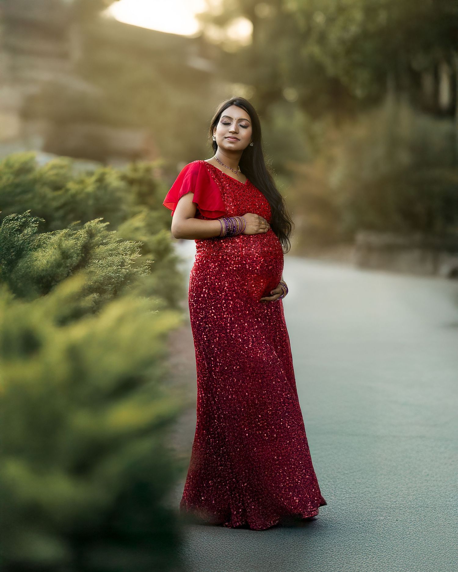 A figure in a sparkling red dress twirls gracefully in an outdoor setting during golden hour.