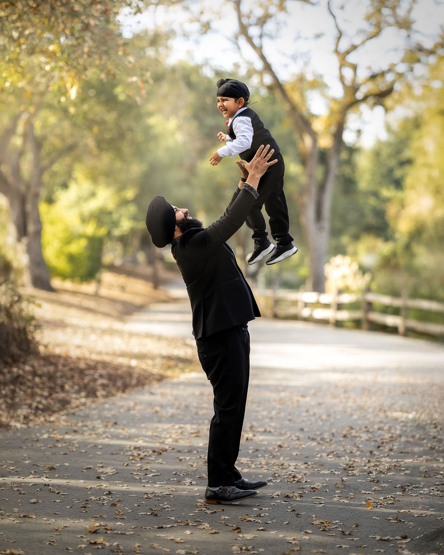 A series of candid outdoor shots showing a playful moment between two people in black clothing on a leaf-covered path.