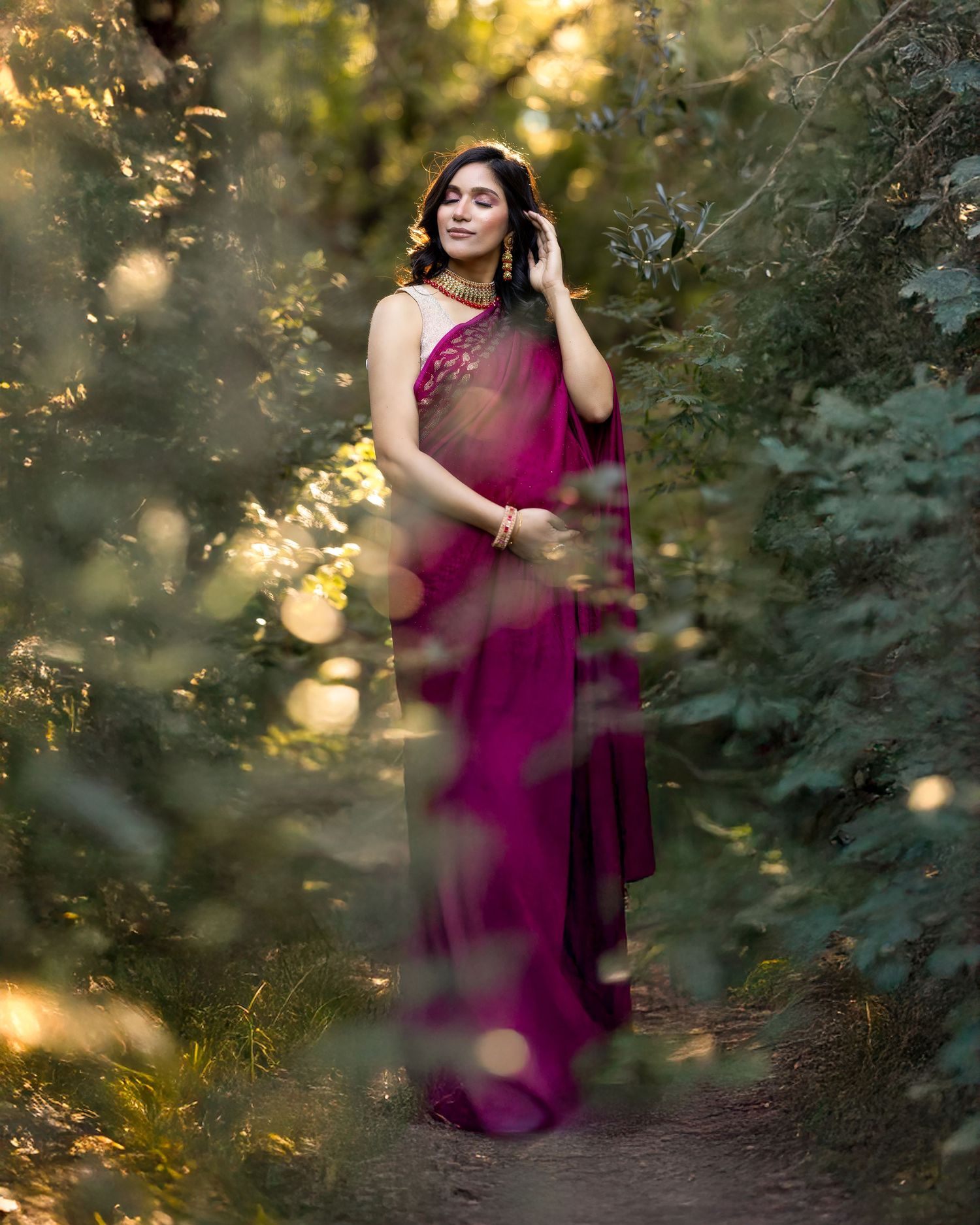 Dreamy outdoor photography featuring a burgundy dress against a natural forest backdrop at sunset.