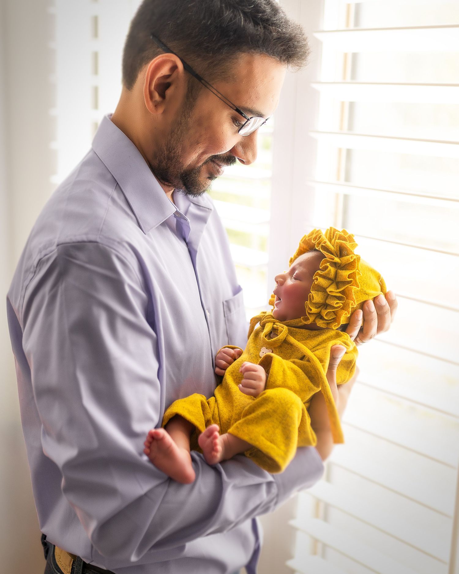A sequence of photos showing someone in a grey shirt holding and kissing a small baby wearing a yellow outfit.