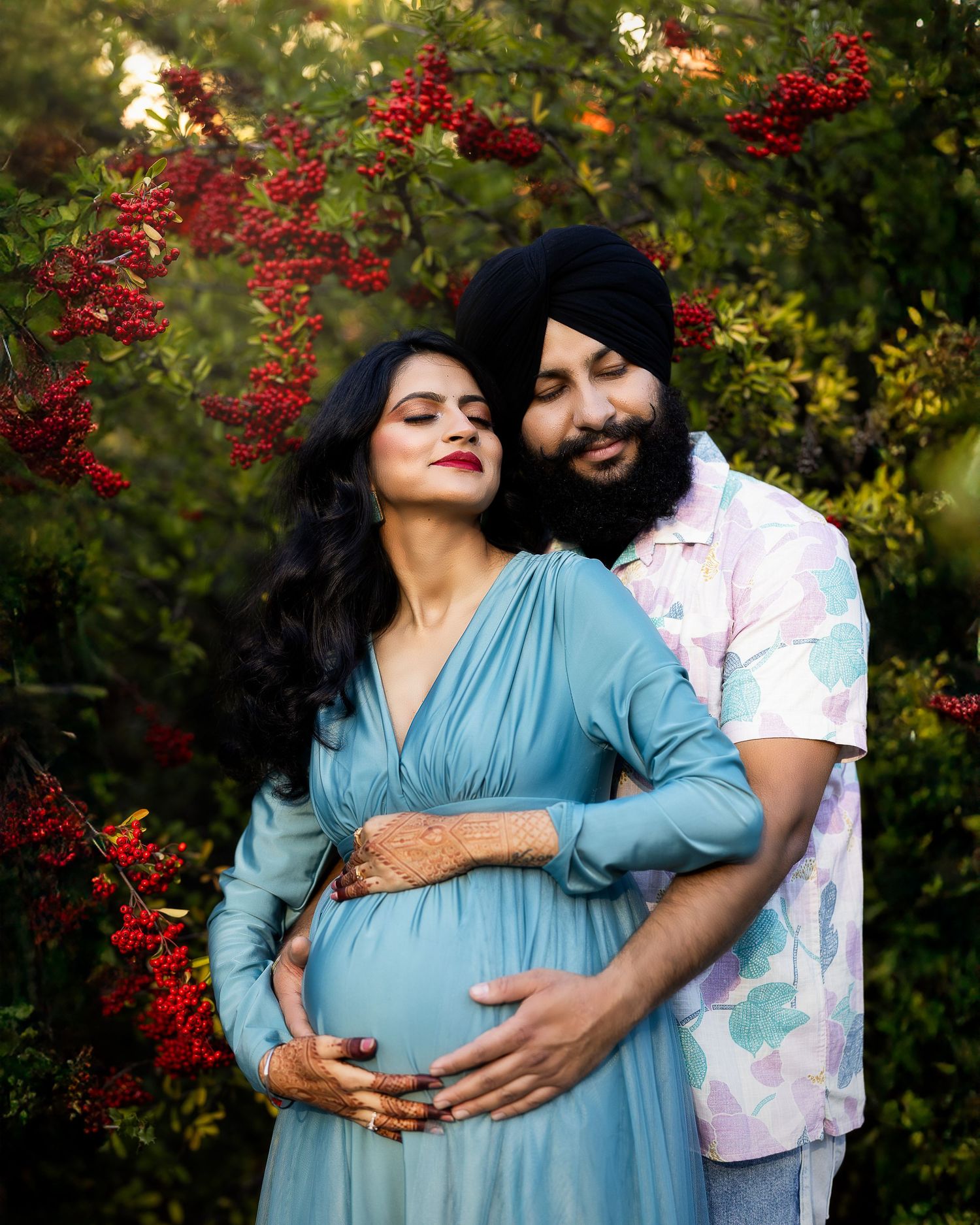 Couple shares tender moments in a garden setting with red berries and greenery as a beautiful backdrop.
