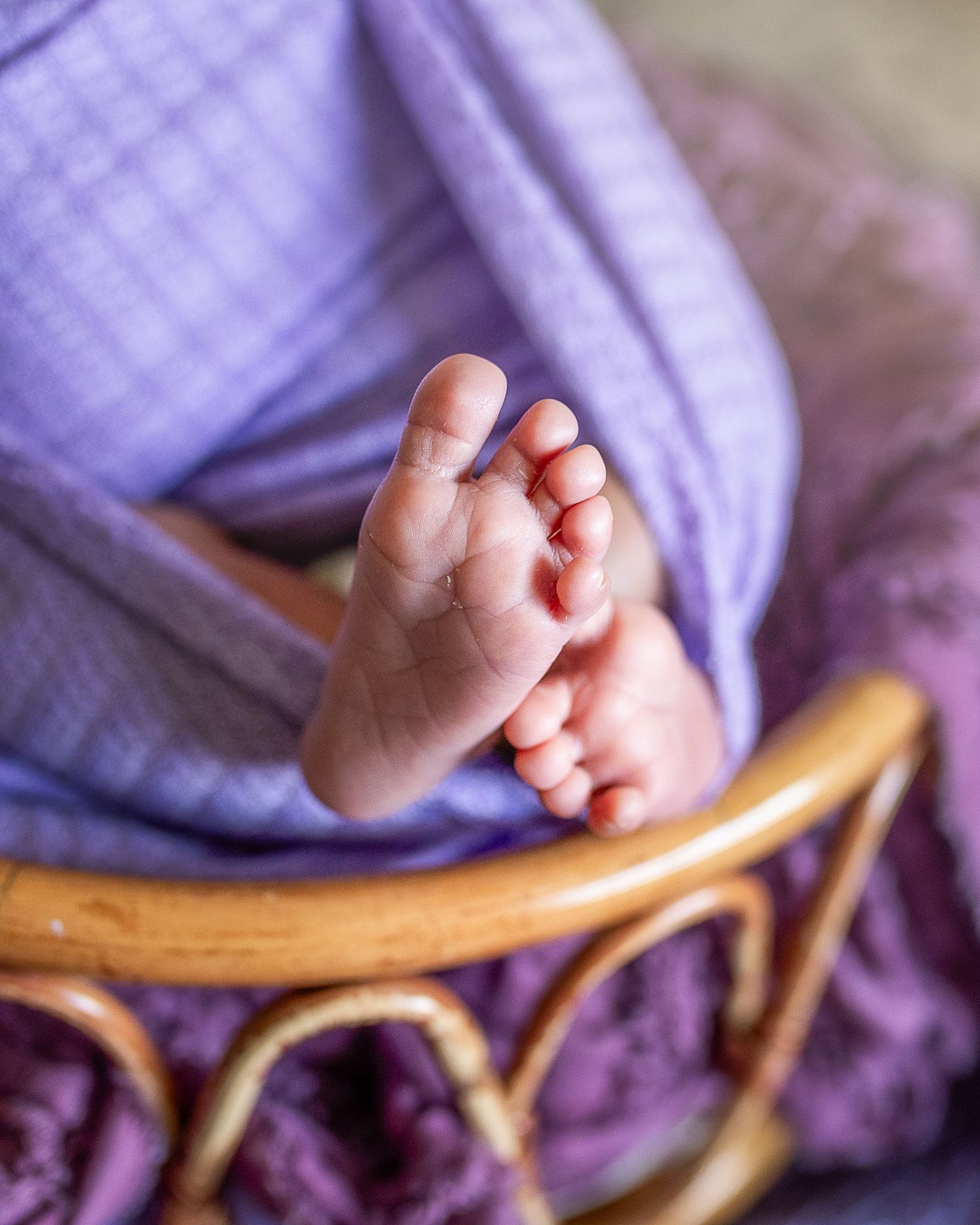 Close-up series of tiny baby feet resting on purple fabric and wooden furniture.