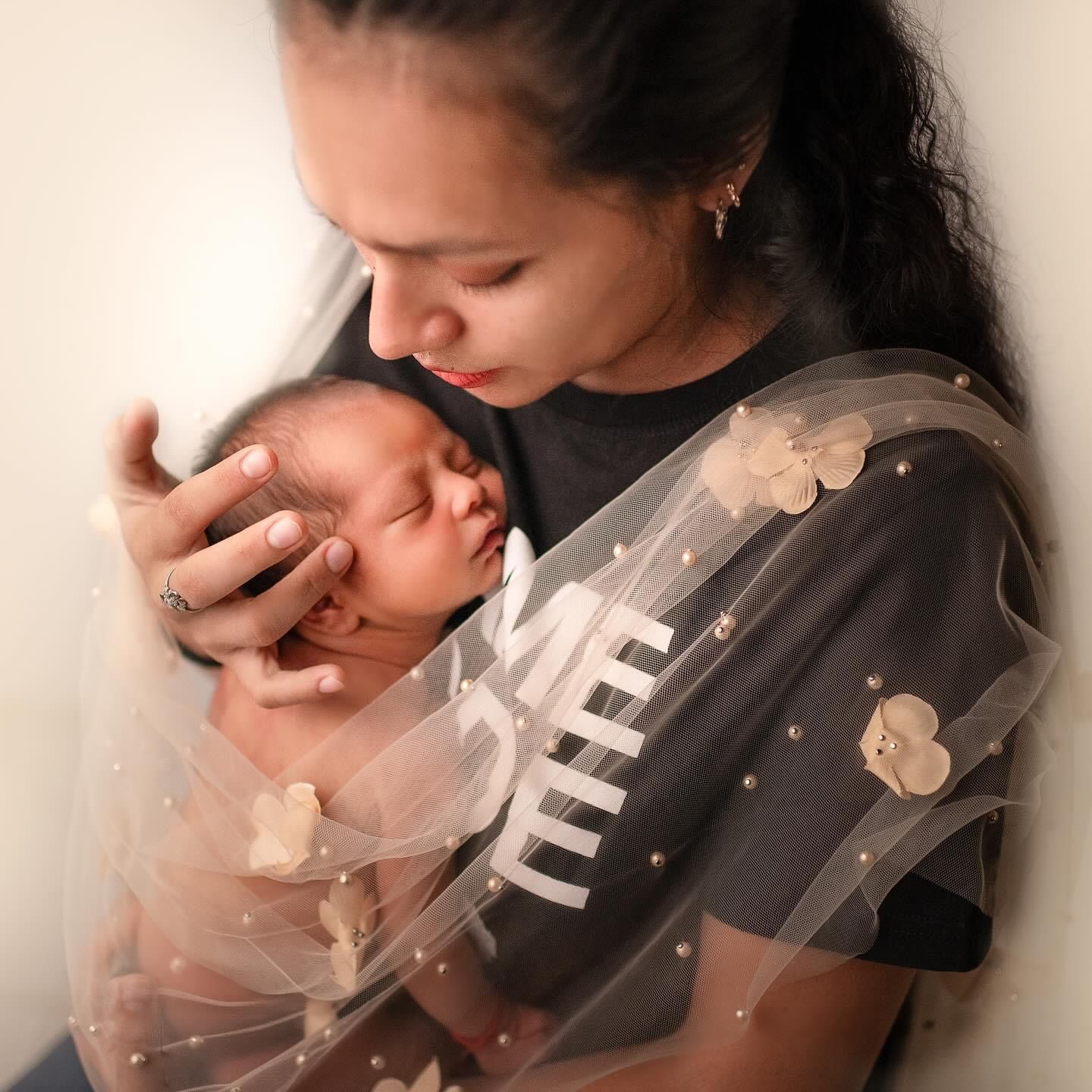 A series of intimate black and white photos showing a person in a dark shirt holding a small baby tenderly.