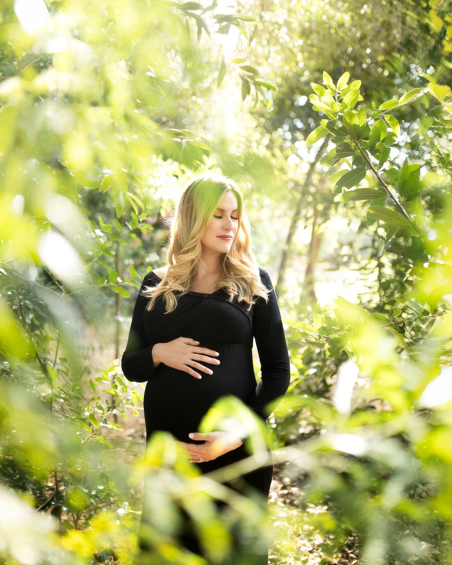 A romantic couple embraces in a sunlit garden with lush green foliage creating a dreamy natural backdrop.
