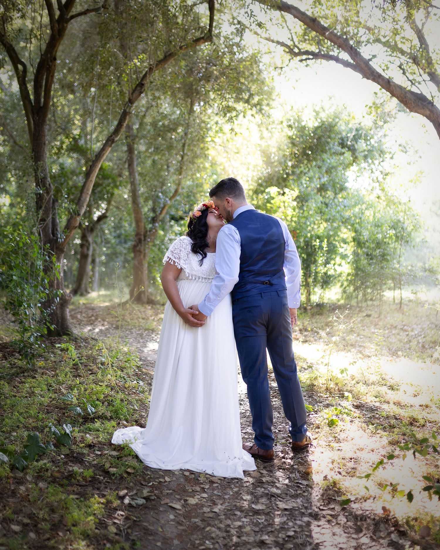 A romantic couple poses together on a wooded forest path during an outdoor photoshoot session.