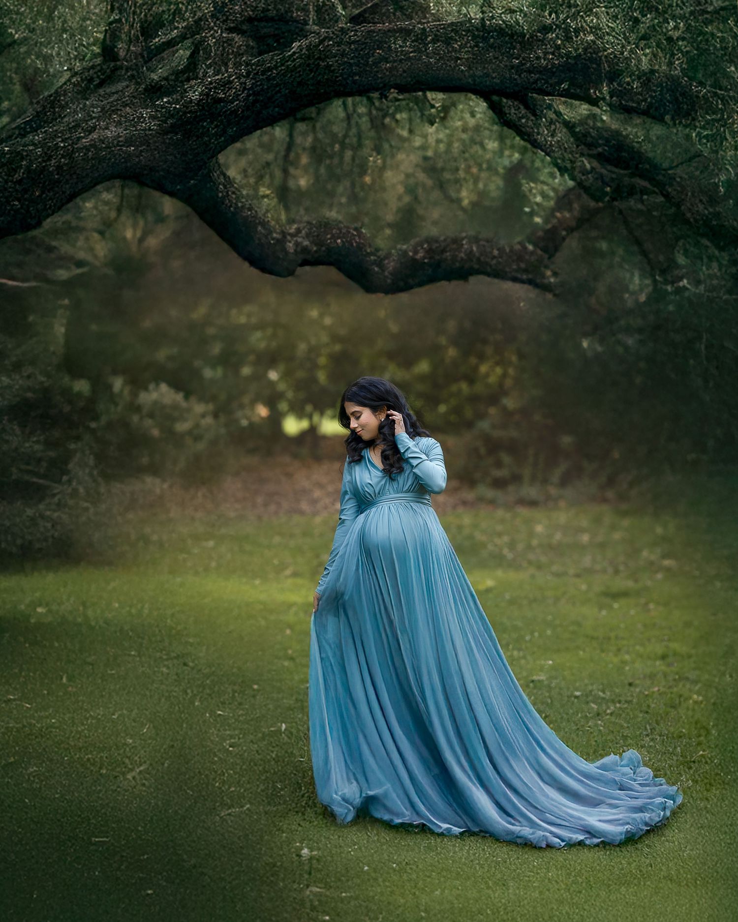 A figure in a flowing blue gown twirls gracefully in a mystical forest setting, creating an ethereal scene.