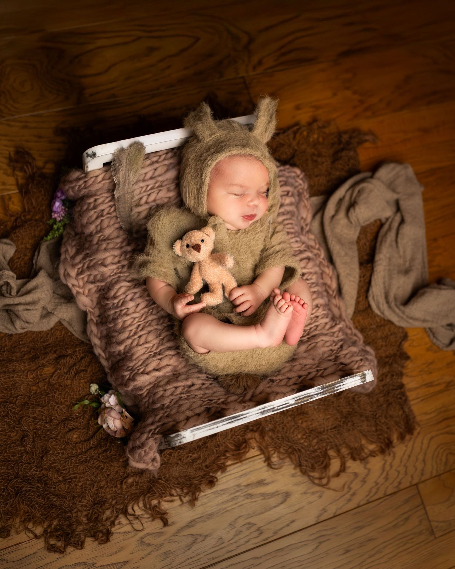 A series of newborn photos showing a sleeping baby nestled in brown textured fabric with soft lighting and artistic angles.