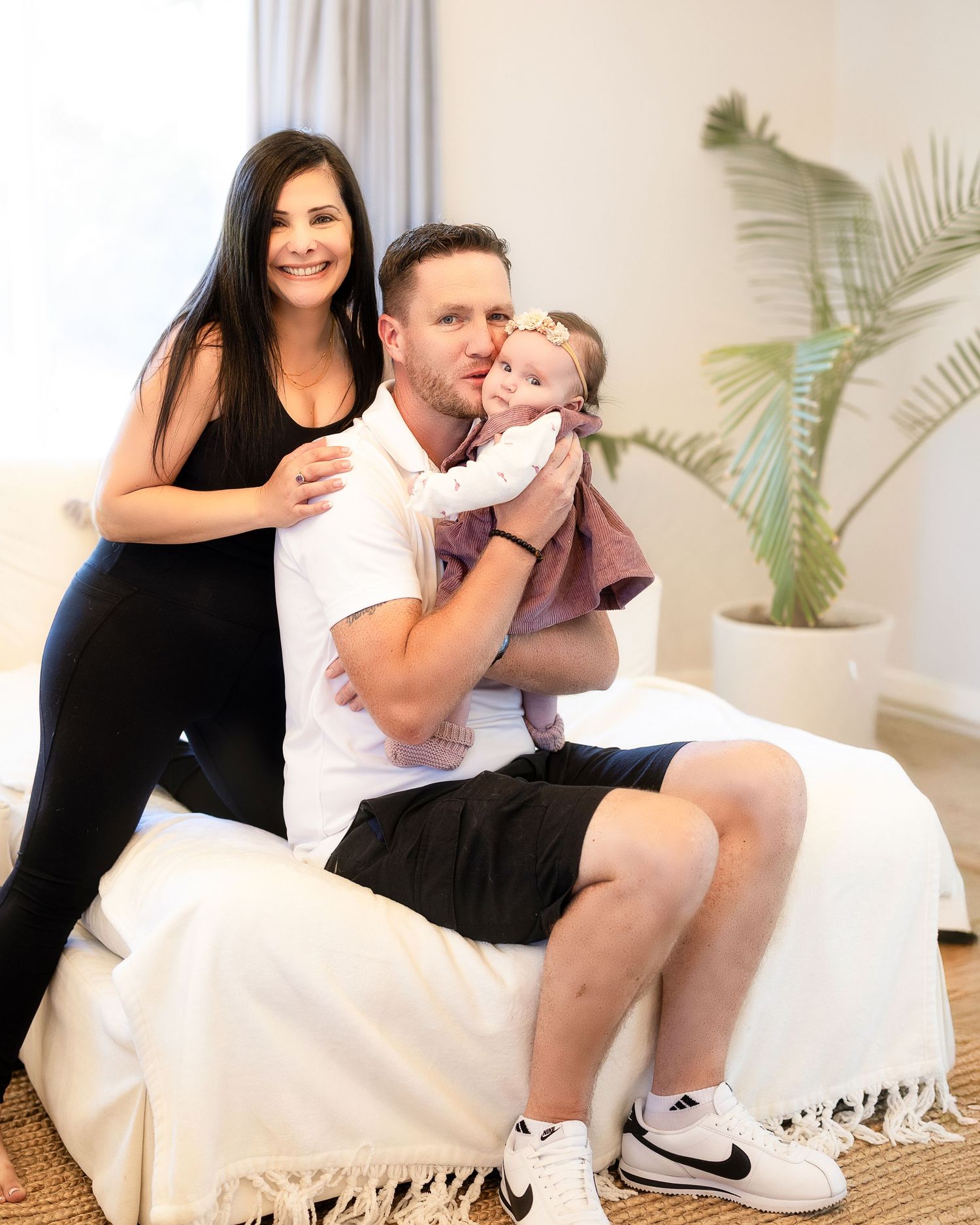 Family enjoying quality time together on white furniture with a houseplant in the background.