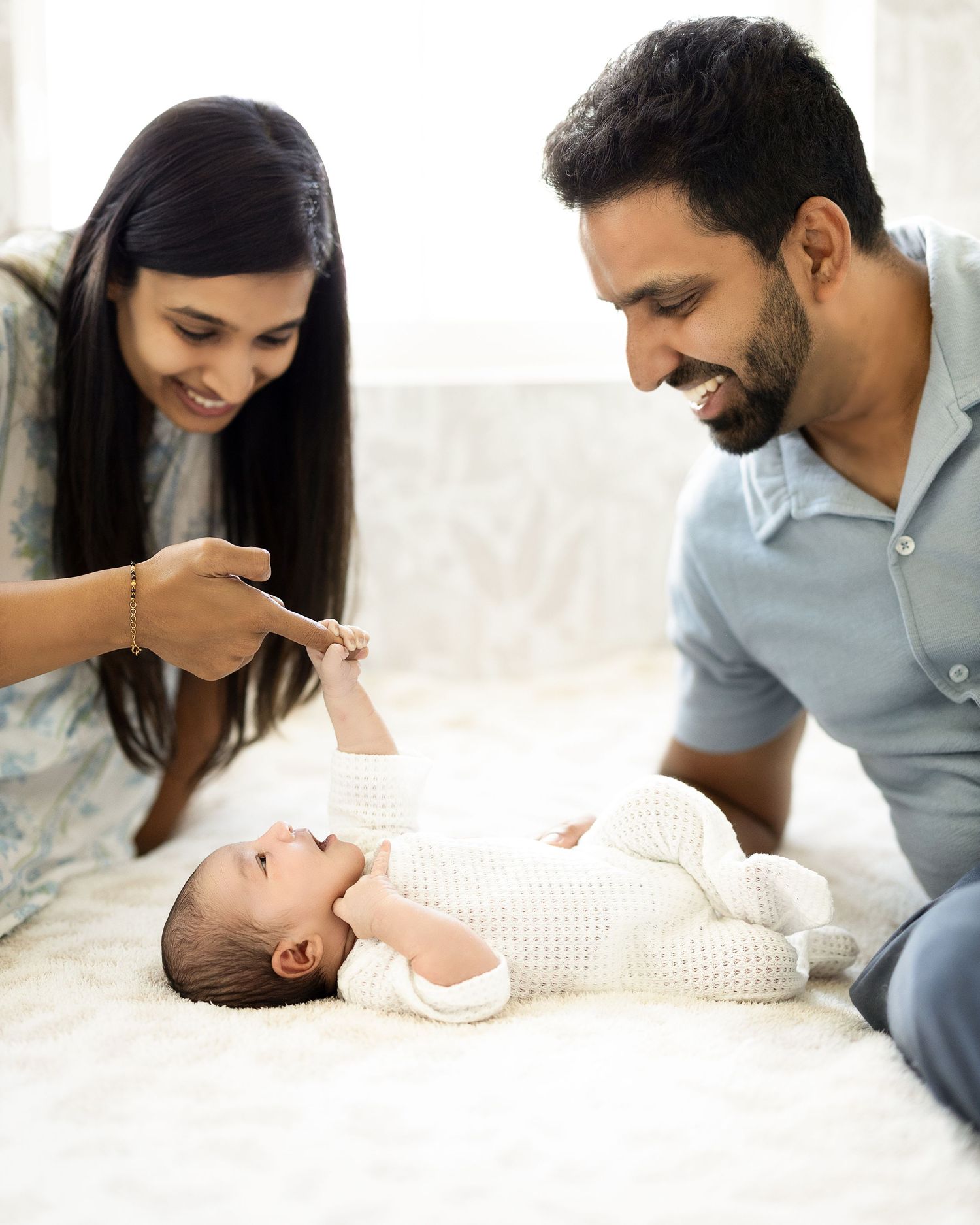 Parents lovingly interact with their newborn baby on a white bed in a series of tender moments.