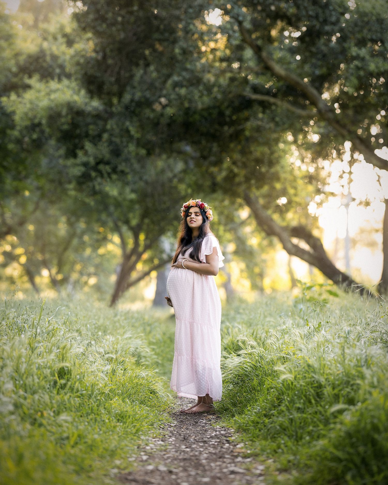 A series of dreamy sunset photos showing two figures embracing in a grassy meadow with sunlit trees in the background.