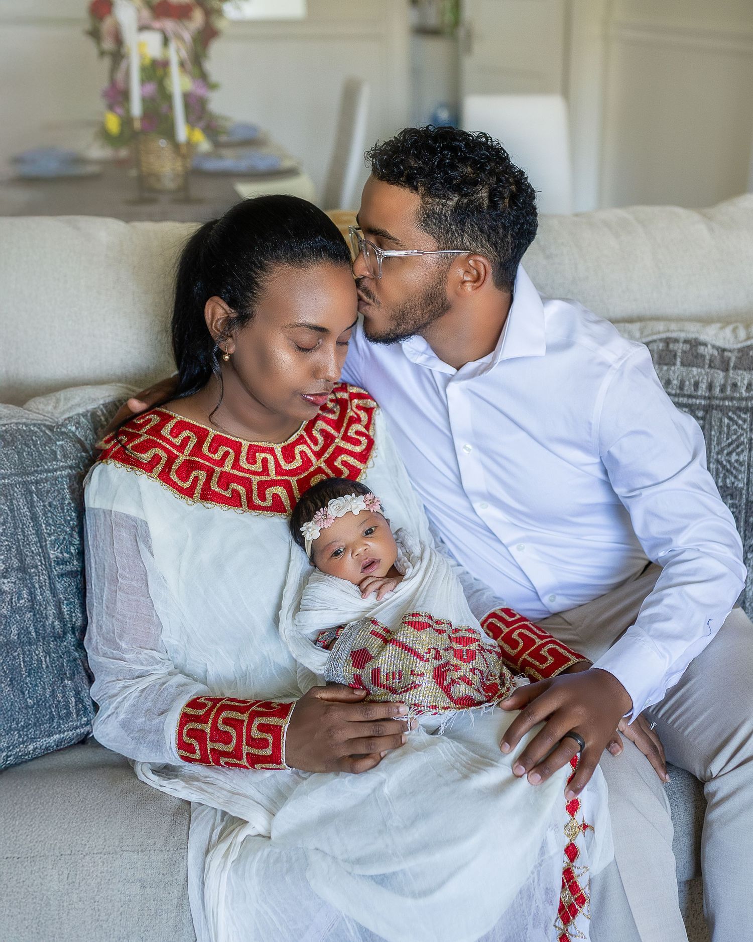 A couple in white and red outfits share intimate moments while lounging together on a couch.