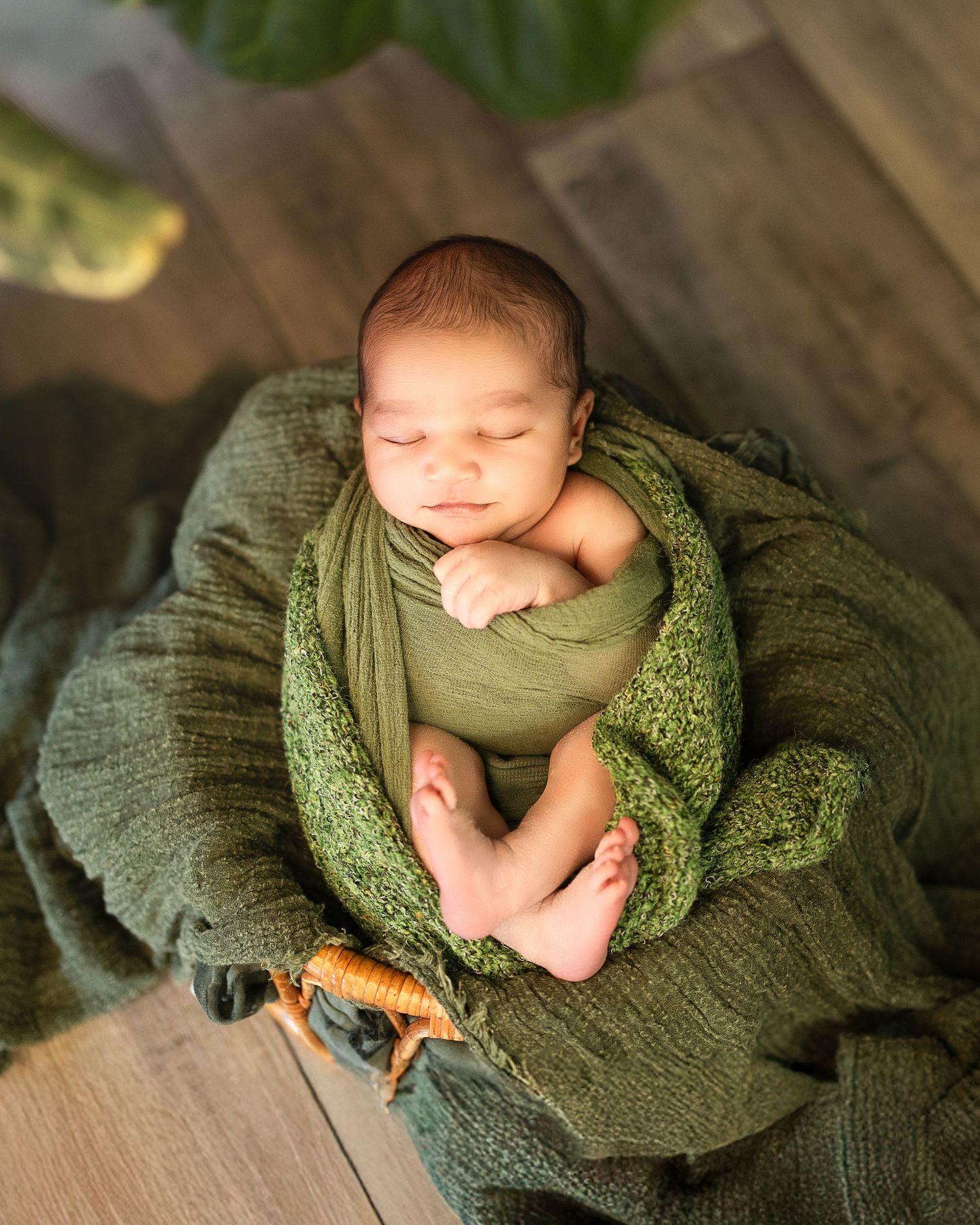 A sleeping newborn wrapped in soft green knit blankets photographed in a series of peaceful poses.