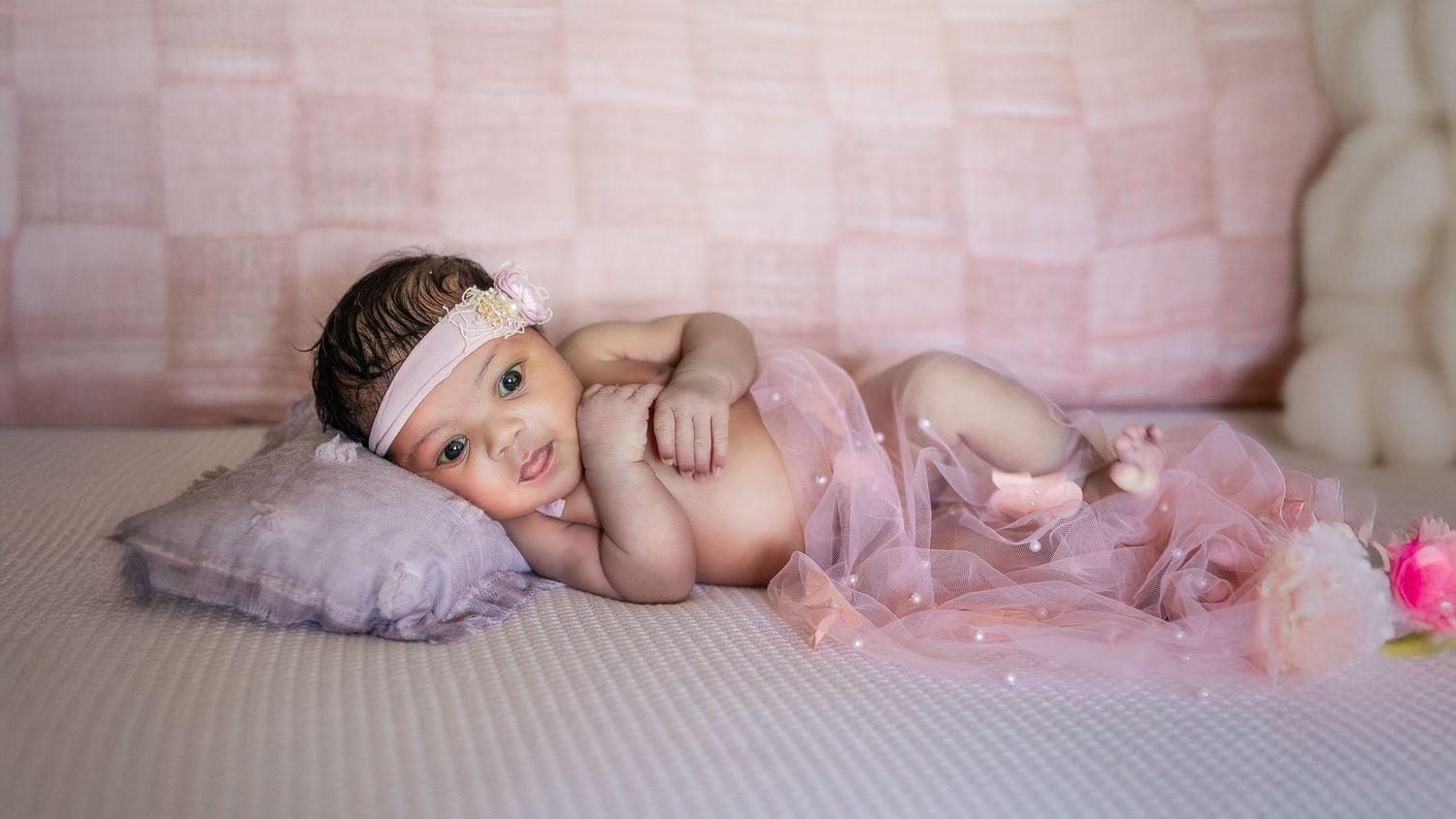 Five connected images show a sleeping baby in pink tulle surrounded by soft blankets and delicate props.