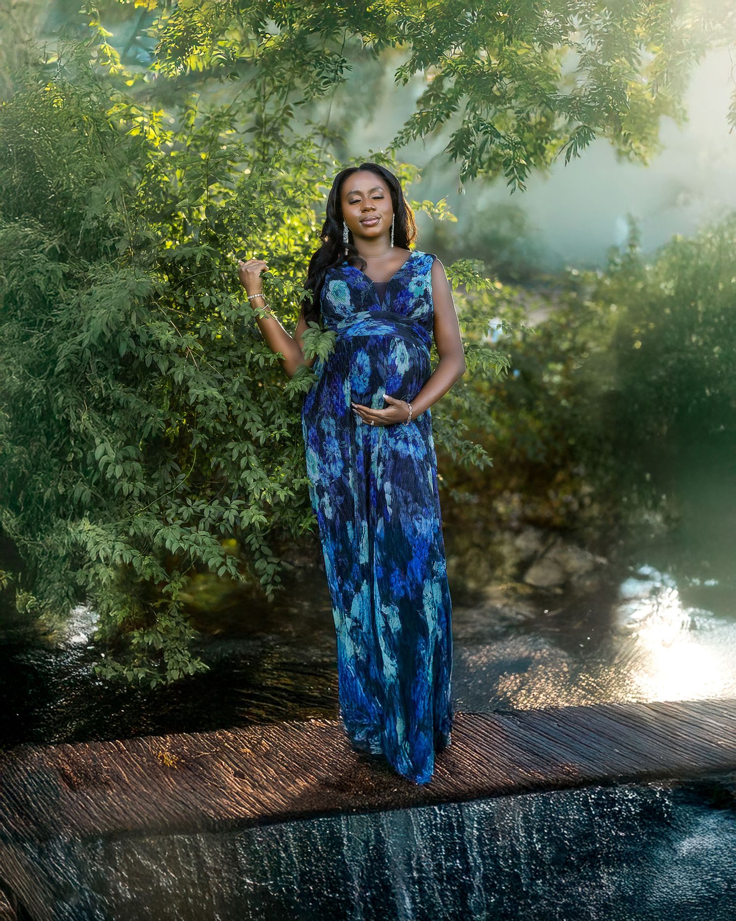 A blue and white tie-dye maxi dress is showcased in a sunlit garden setting with lush greenery in the background.