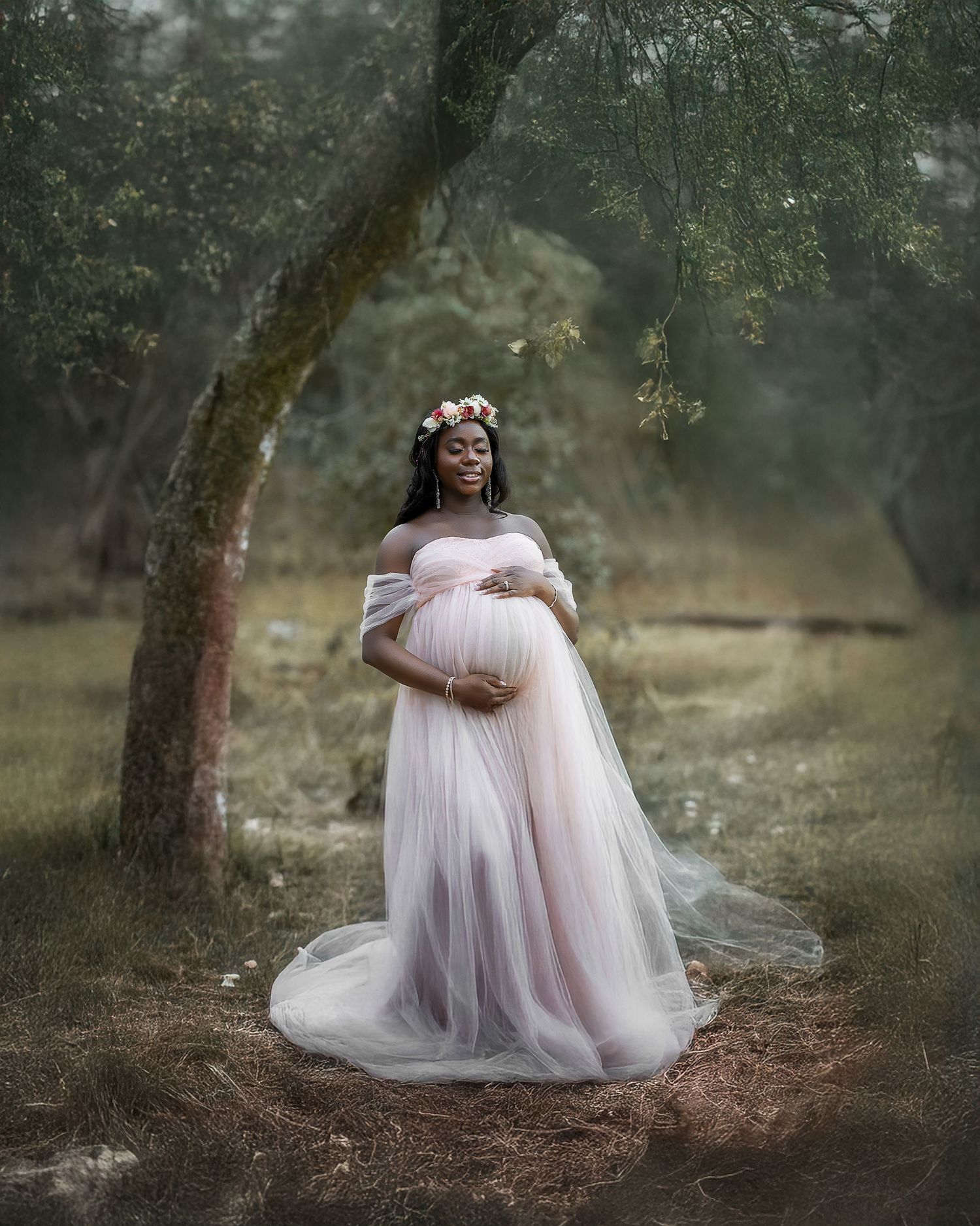 A dreamy maternity photoshoot in a misty forest with a person wearing a flowing pink tulle gown.