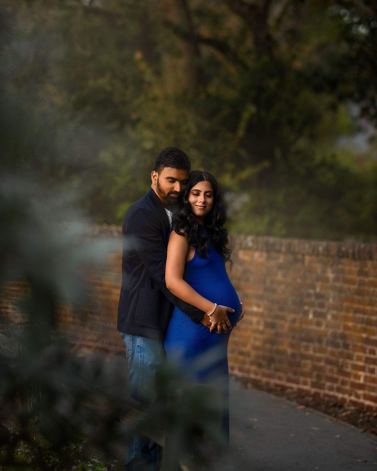 A couple shares an intimate moment together against a brick wall backdrop in a romantic outdoor setting.