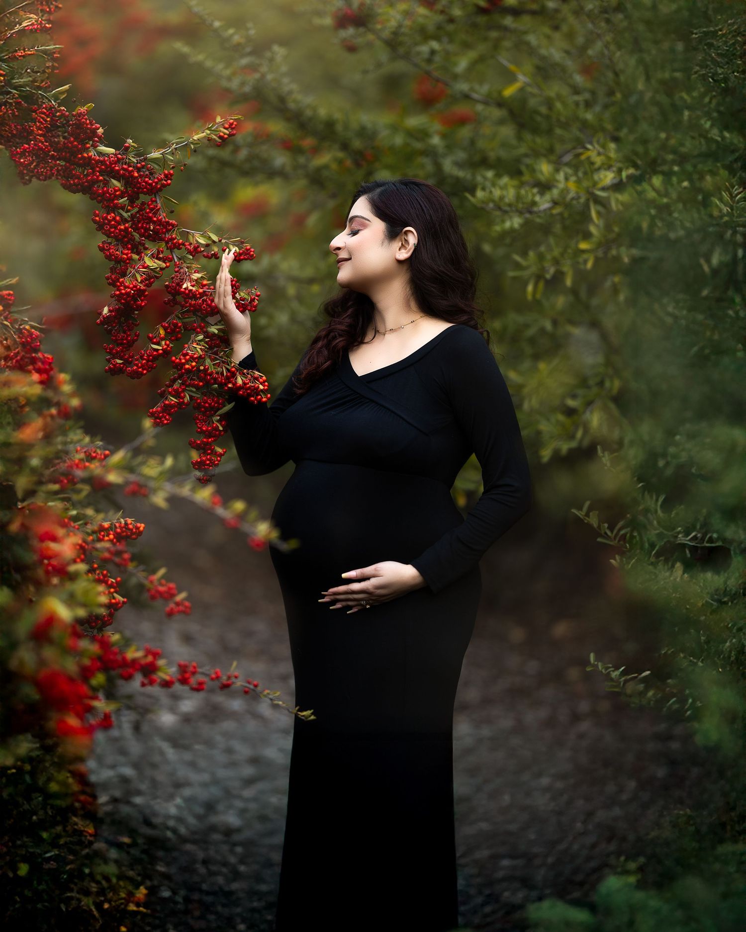 Figure in black clothing reaches toward vibrant red berries on branches in moody outdoor setting.