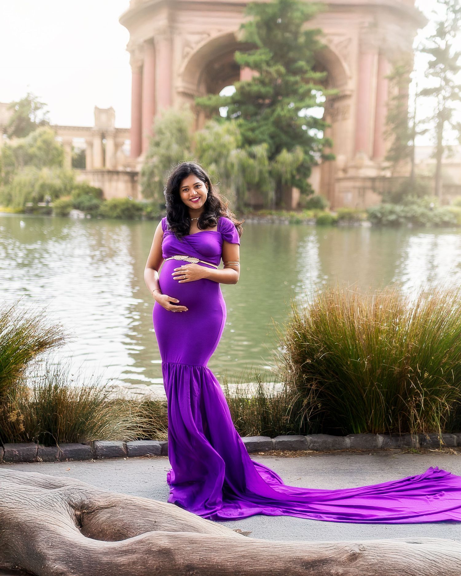 A maternity photoshoot at the Palace of Fine Arts in San Francisco features flowing purple gown against scenic lake backdrop.