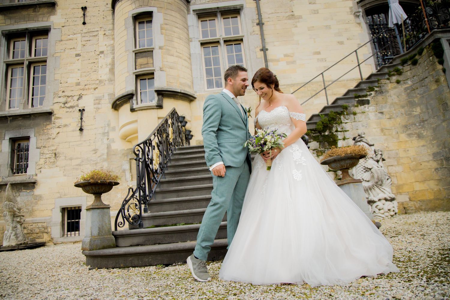 Elegant couple poses on historic stone staircase in formal wedding attire.
