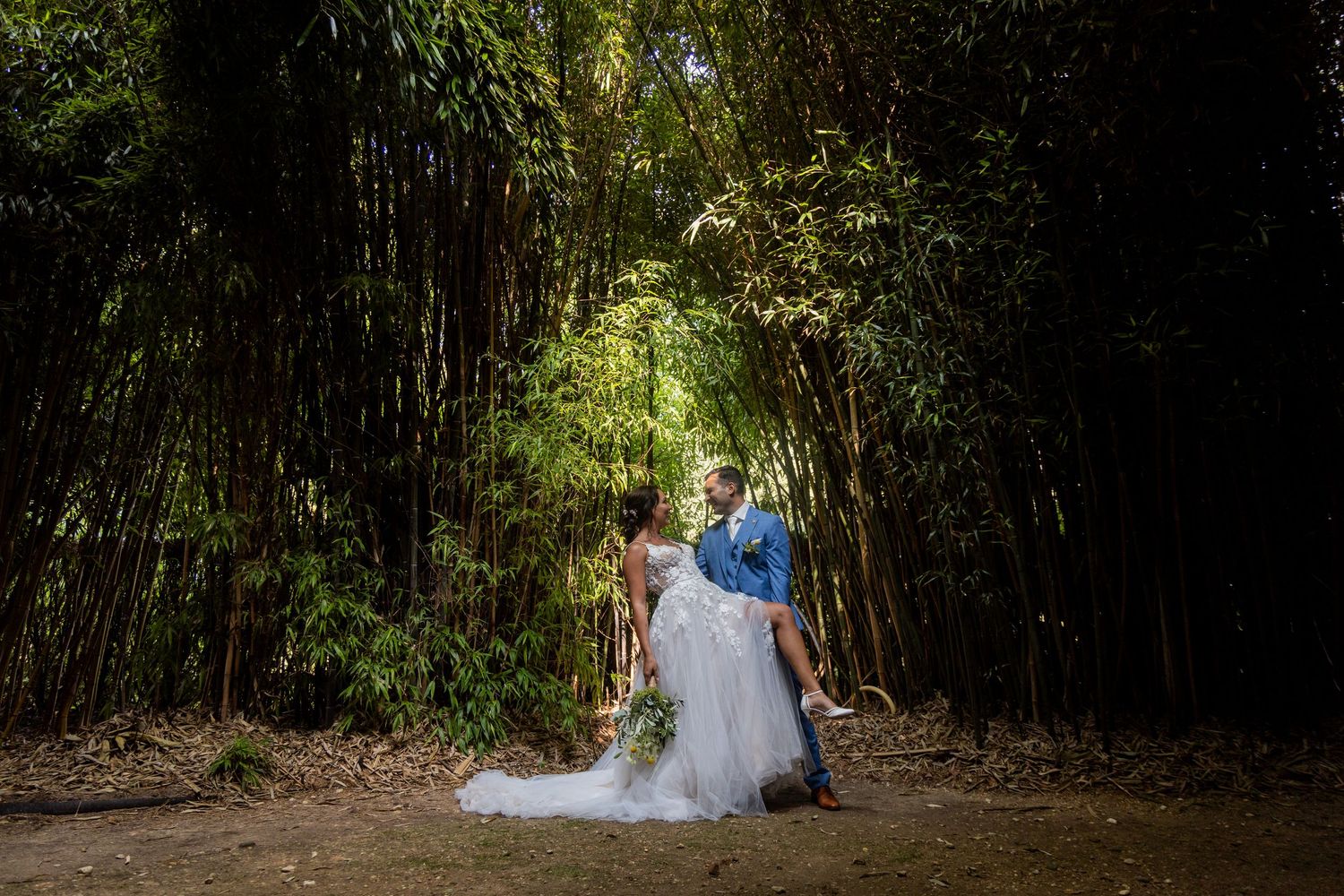 Newlyweds pose in enchanting bamboo forest setting with dramatic lighting.