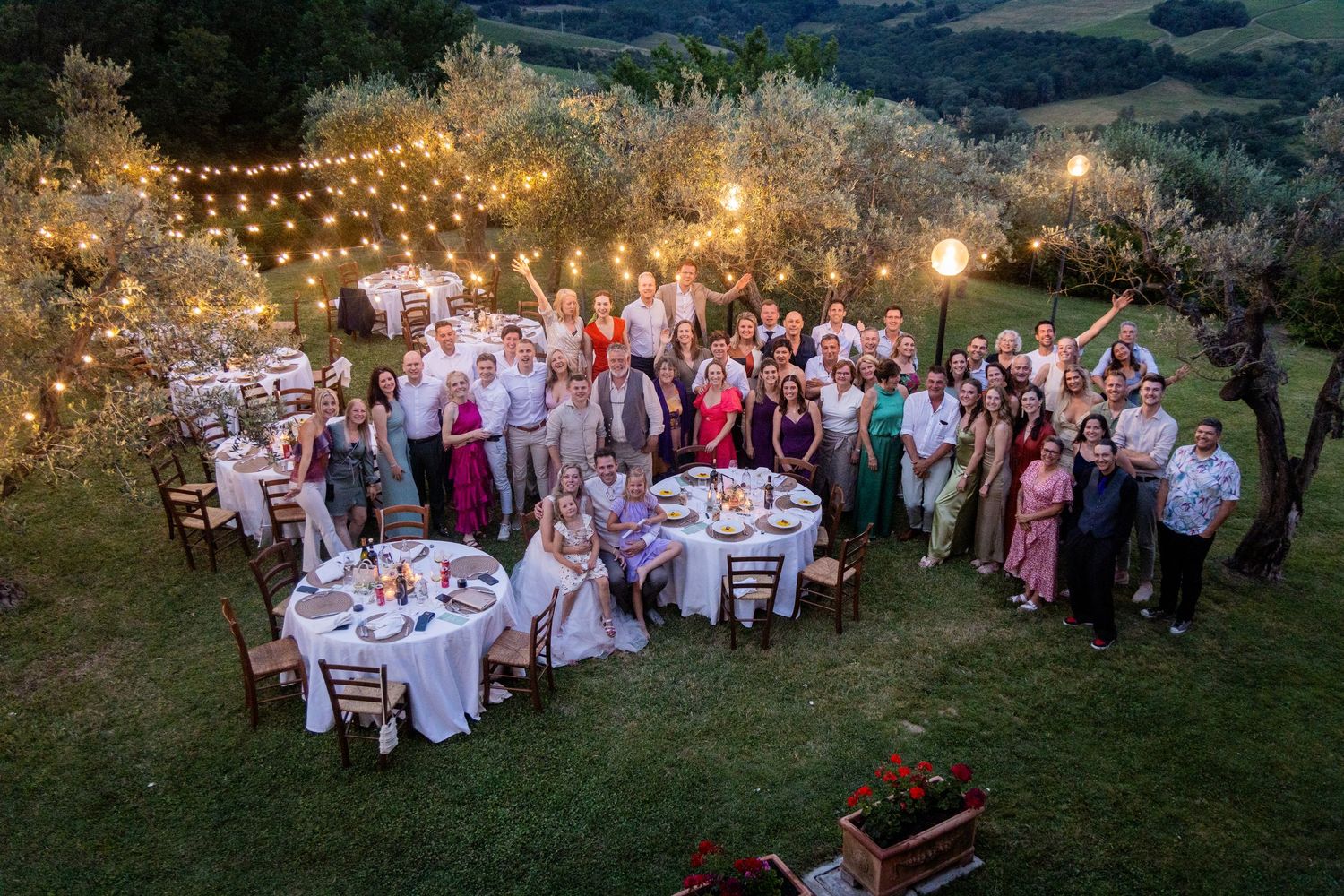Wedding reception dinner tables with string lights illuminate an outdoor evening celebration under a starry sky.