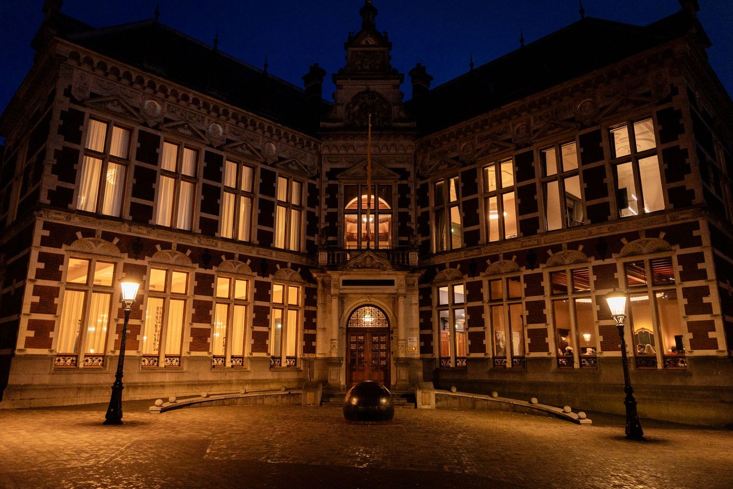 Historic university building illuminated at night with gothic architecture and ornate windows.
