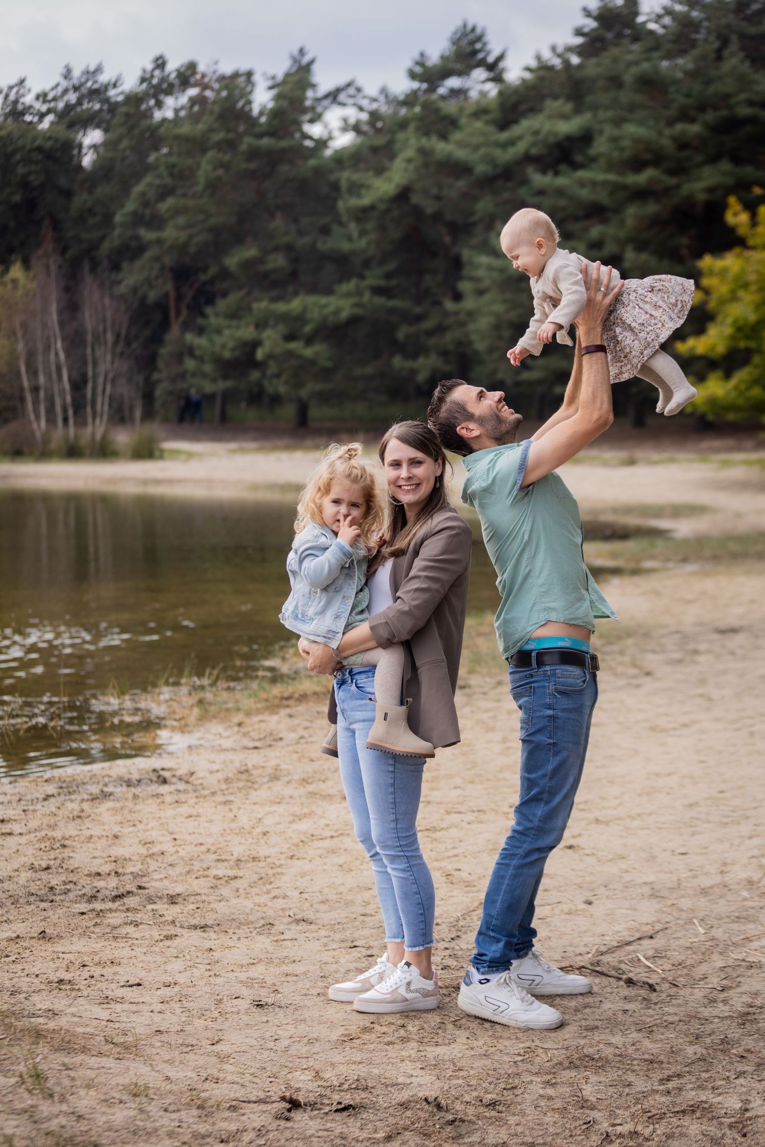 Family enjoying a playful moment together by a serene lake.