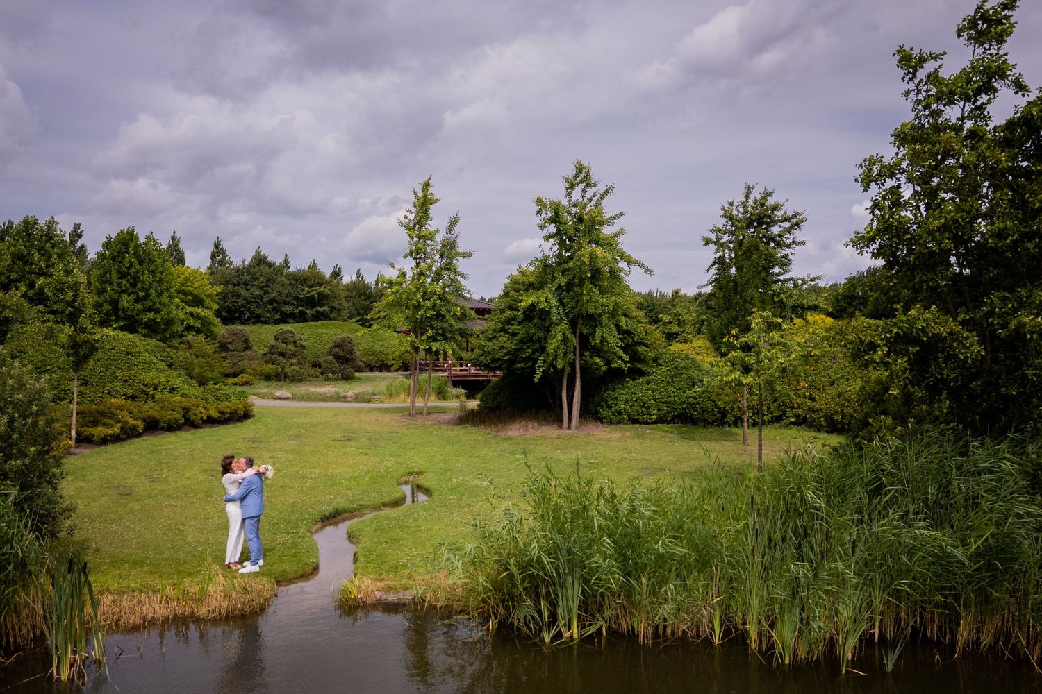 A scenic view of a golf course with a pond, lush greenery, and two golfers on a curved path.