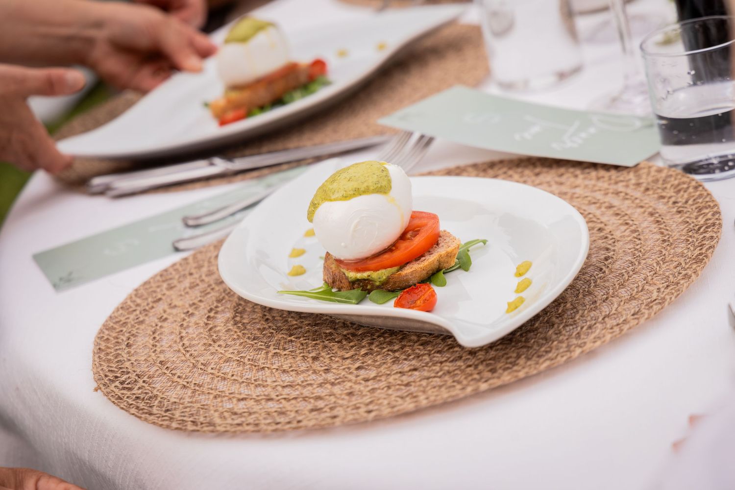 Dining table setting with multiple plates of eggs benedict topped with hollandaise sauce and garnished with fresh herbs.