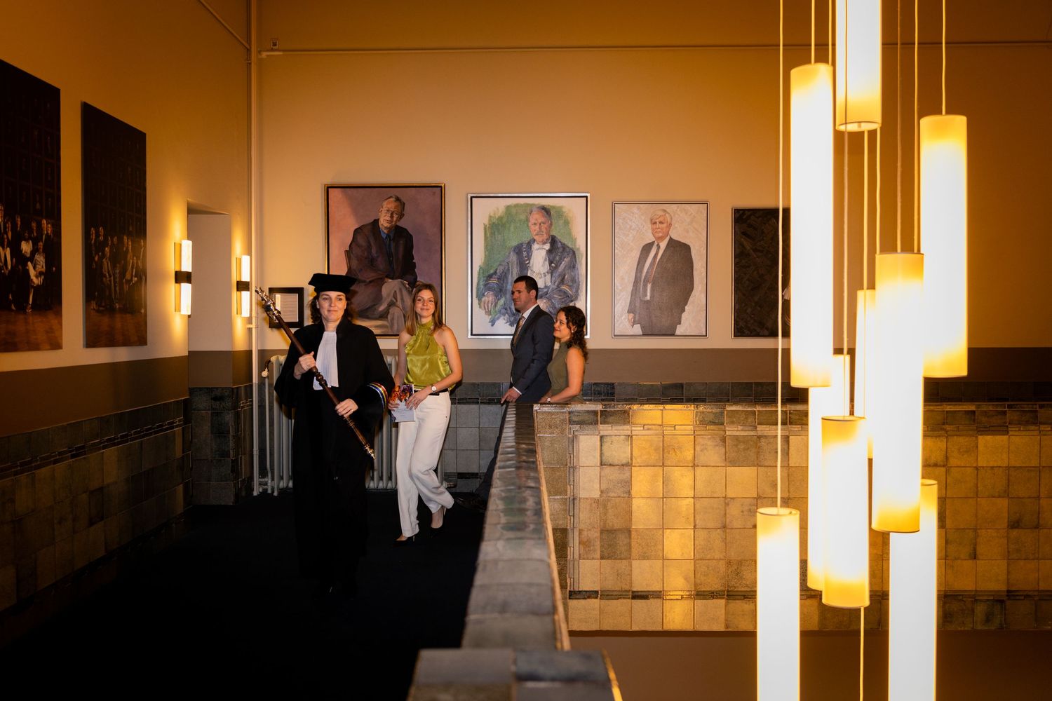 People gathering in a warmly lit hallway with formal decor.