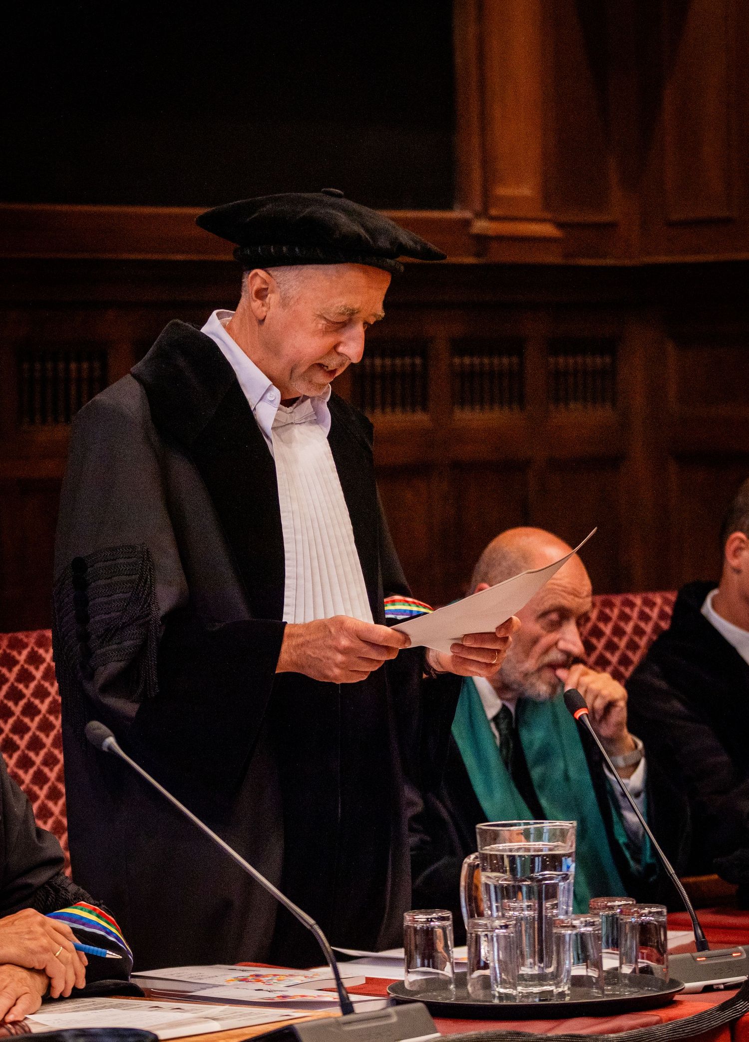 Senior academic in traditional robes reviews documents during formal ceremony.