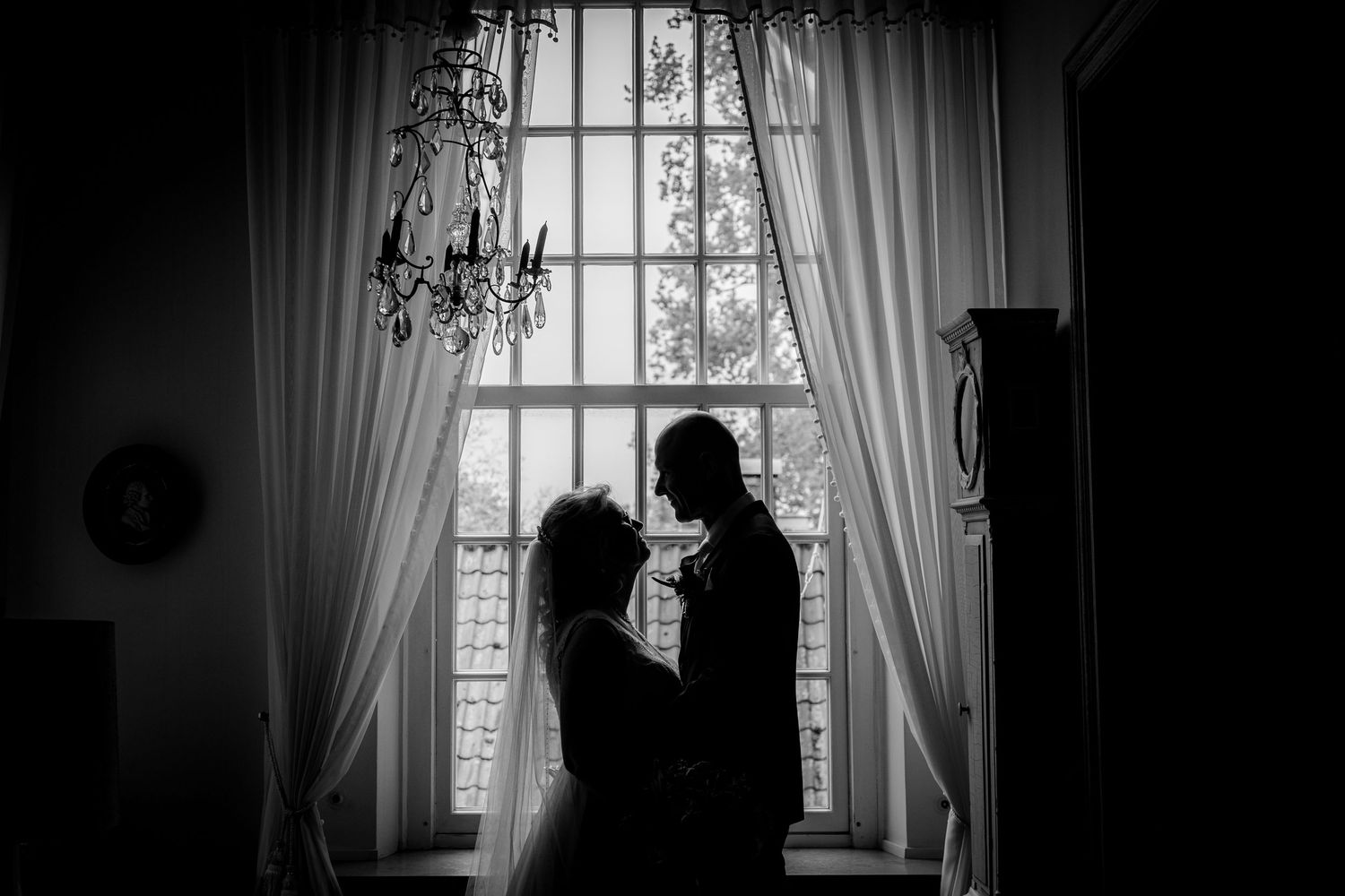 Silhouettes create dramatic window-framed portraits in black and white wedding photography.