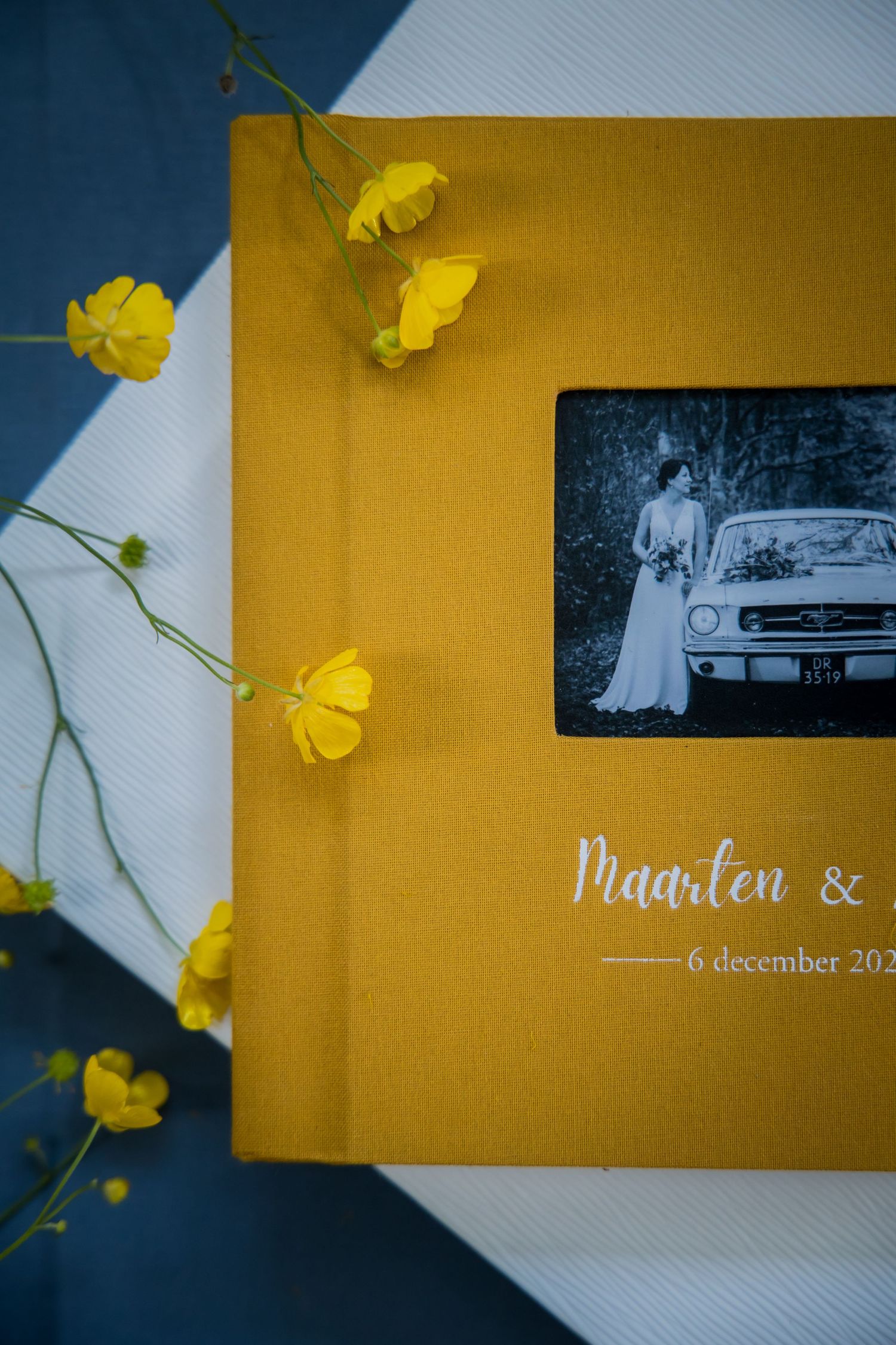 Yellow wedding album with vintage black and white photo and delicate yellow buttercup flowers as decoration.