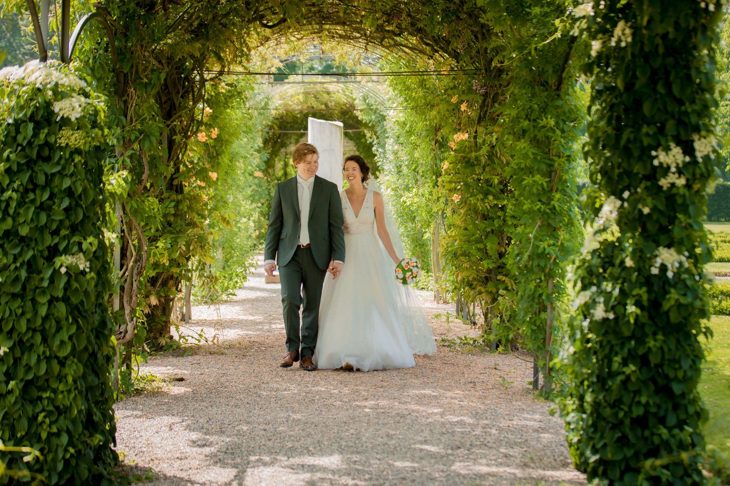 Sunlight filters through vine-covered garden arches creating a romantic walkway.