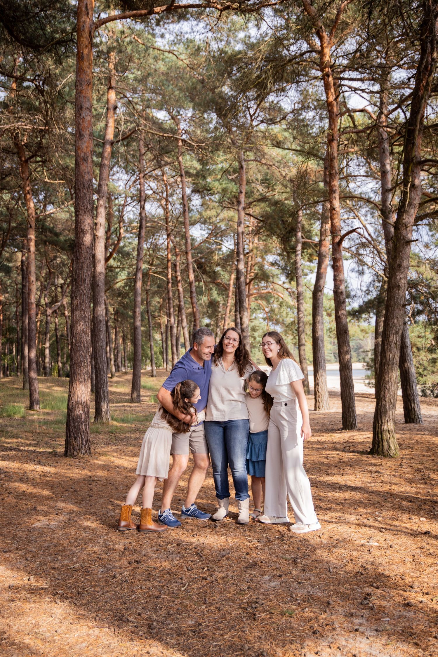 Family group posing for a portrait among tall pine trees.
