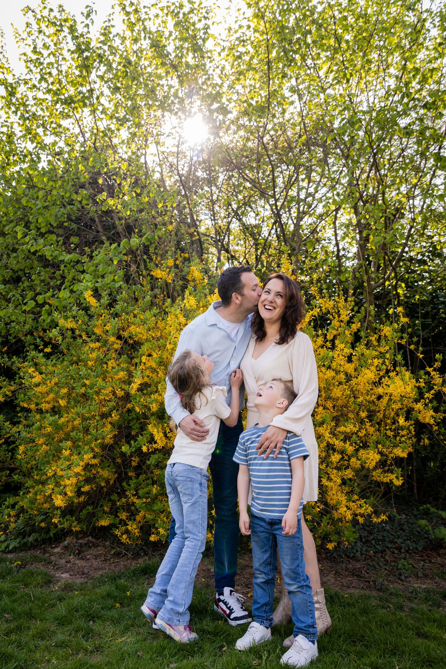 A happy family moment captured against blooming yellow forsythia bushes in springtime.