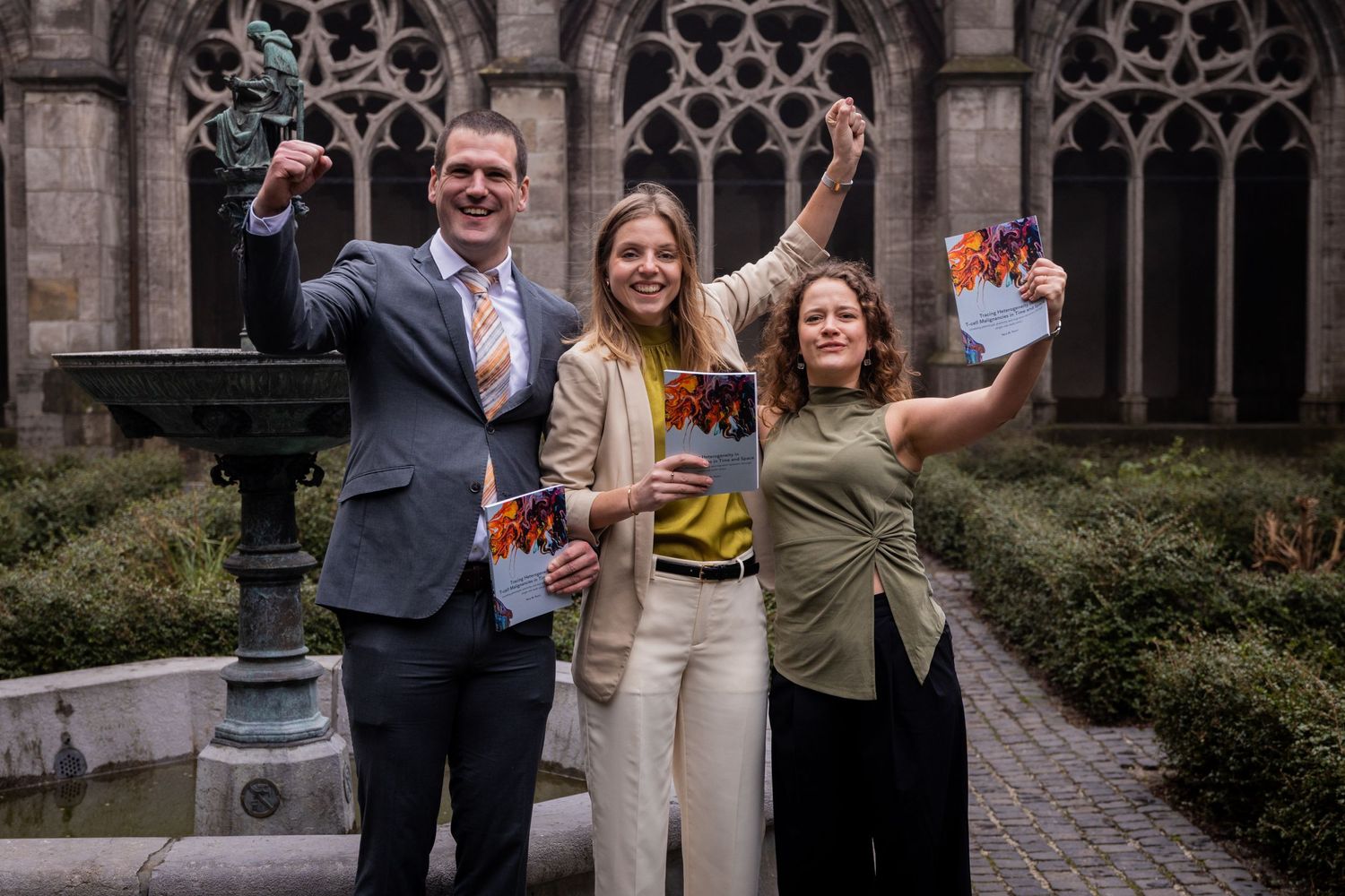 Group celebrating with books in front of gothic architecture.