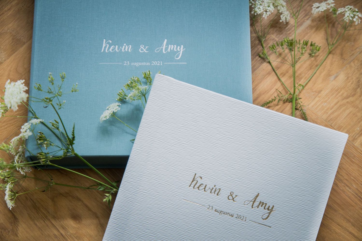 Wedding invitation suite featuring elegant gray and blue stationery pieces displayed on a rustic wooden surface.
