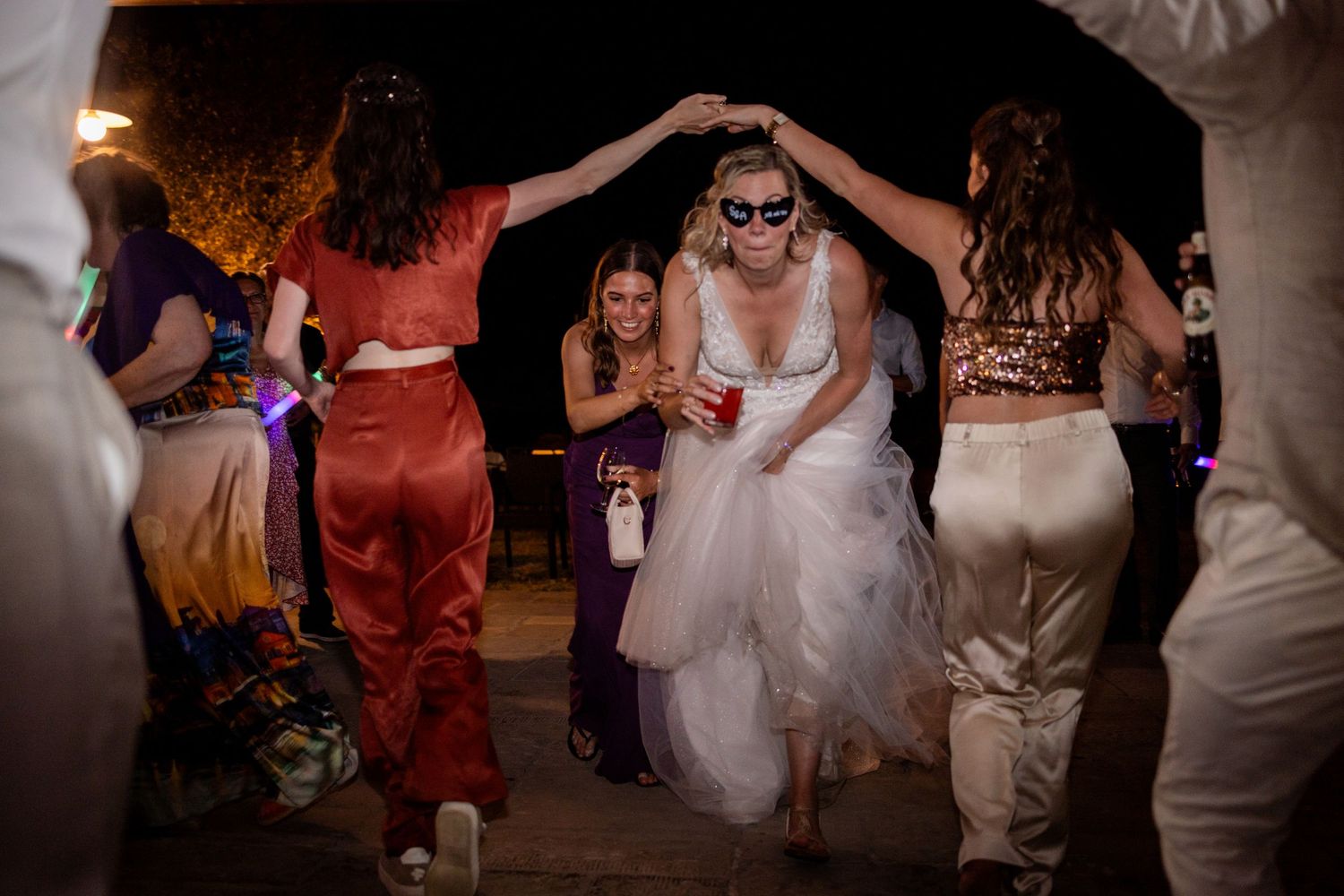 A group of people dancing together at a wedding reception in formal attire.