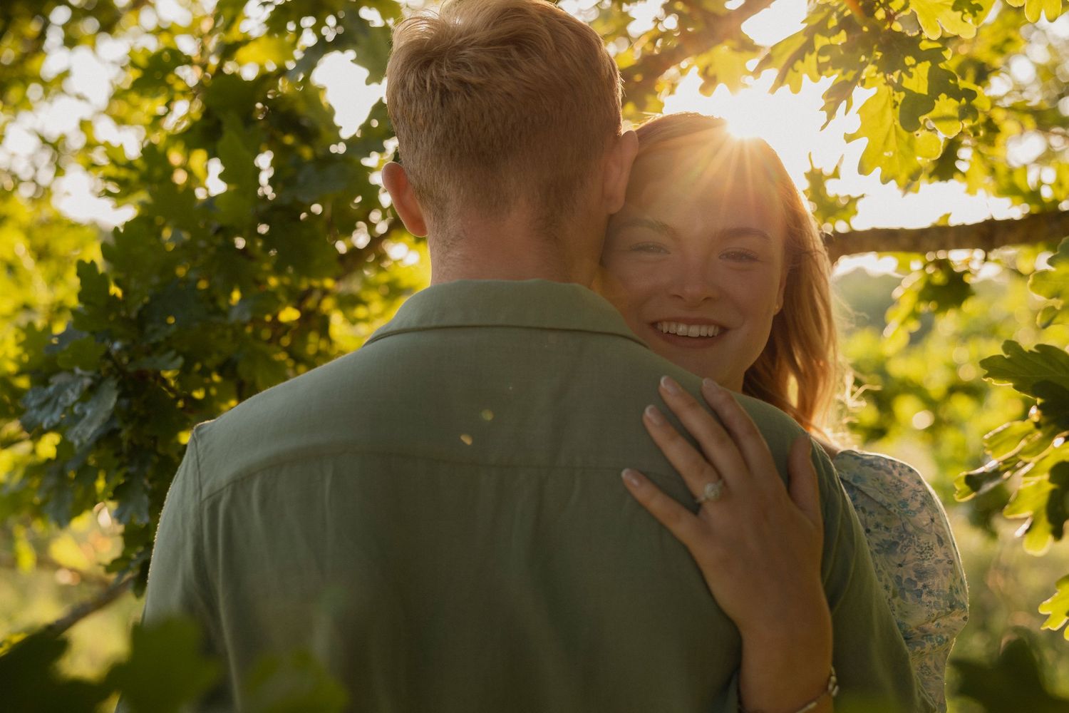 Couple embracing in a sunlit garden with golden autumn leaves creating a romantic atmosphere.