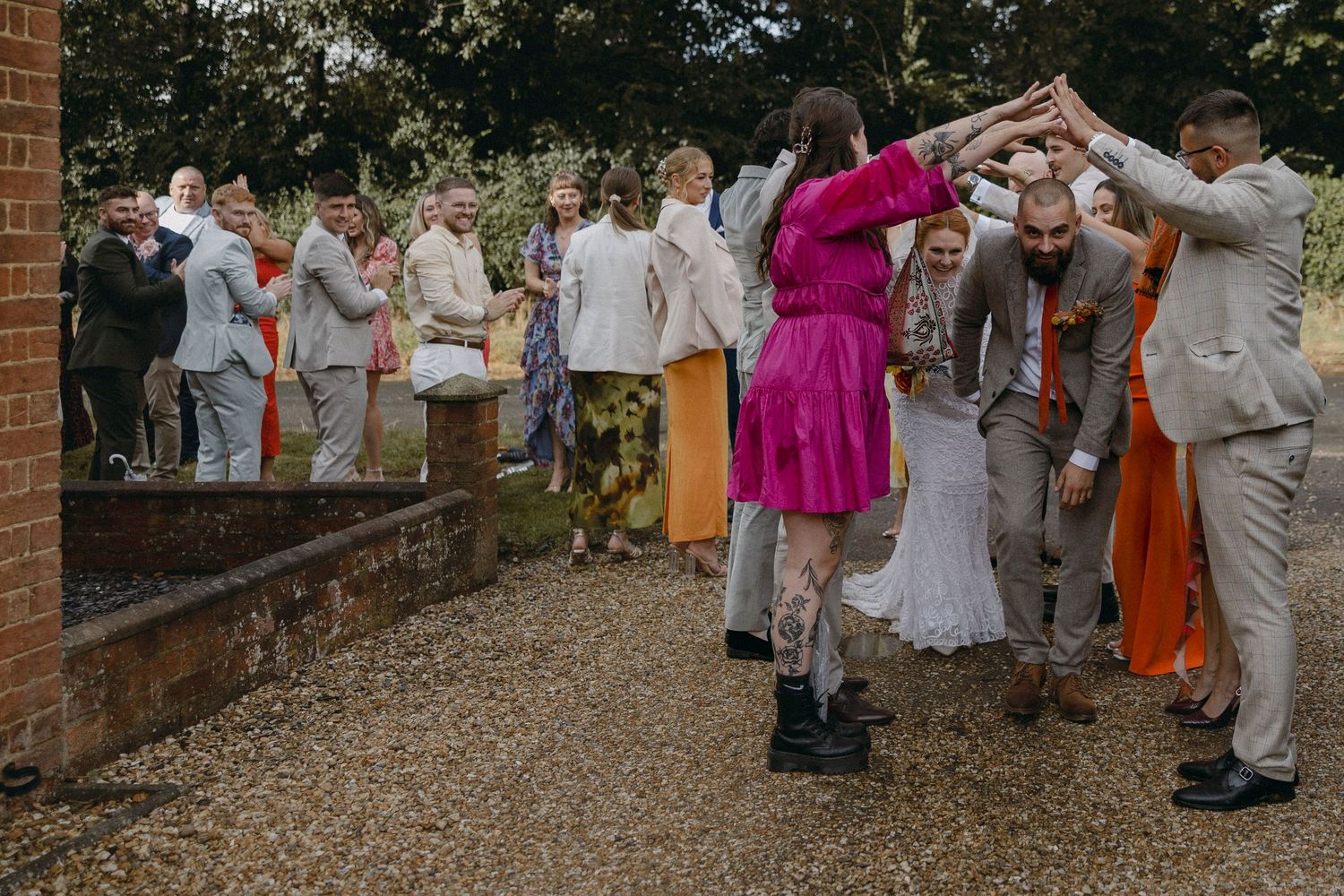 Wedding guests forming a tunnel arch for the bride and groom at an outdoor garden ceremony celebration.