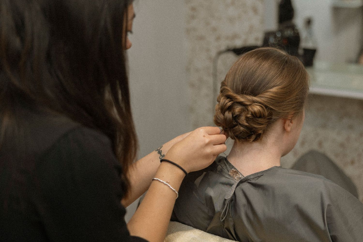 Hairstylist creating an elegant braided updo on a client at a professional hair salon.