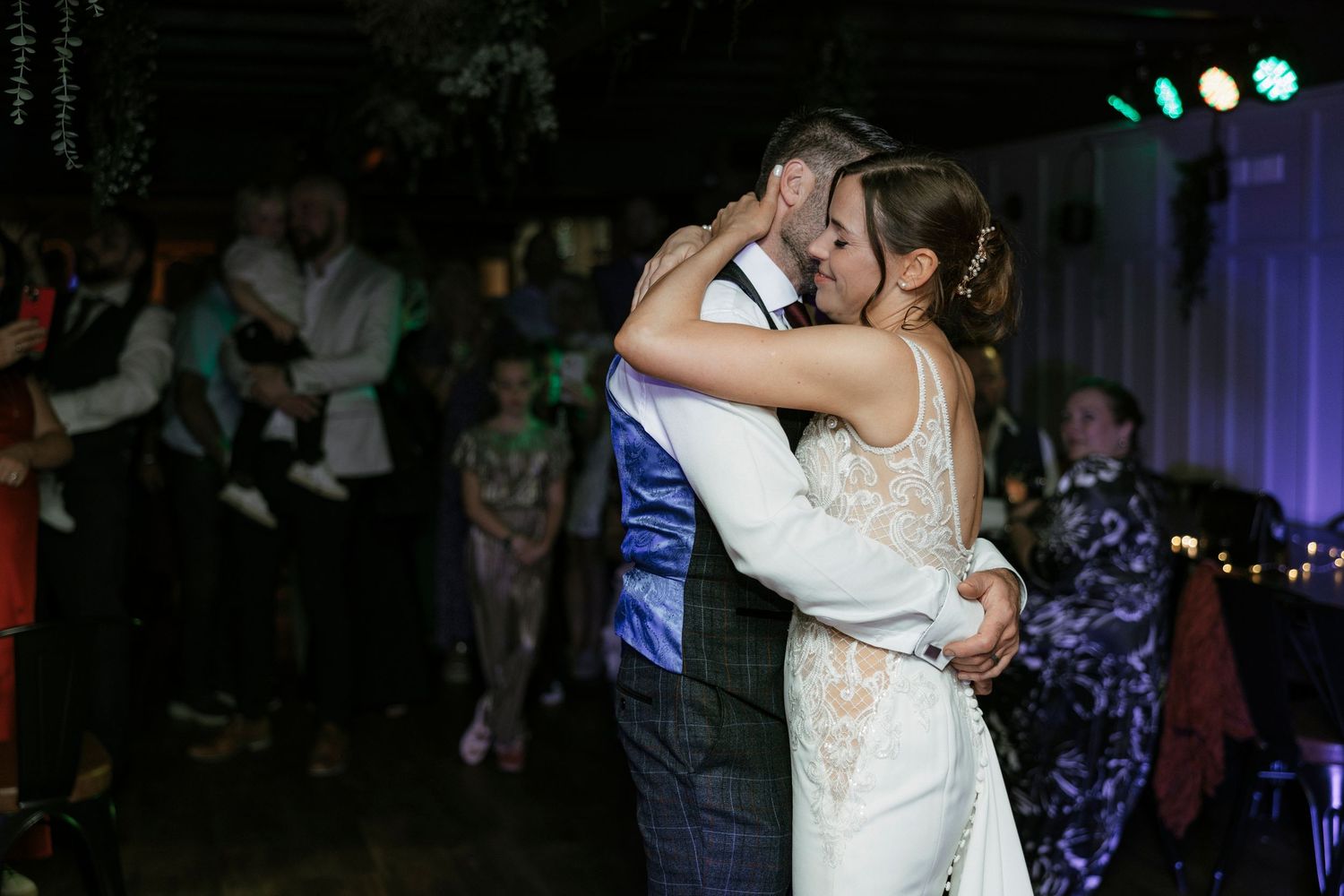 Bride and groom sharing first dance embrace at romantic wedding reception.
