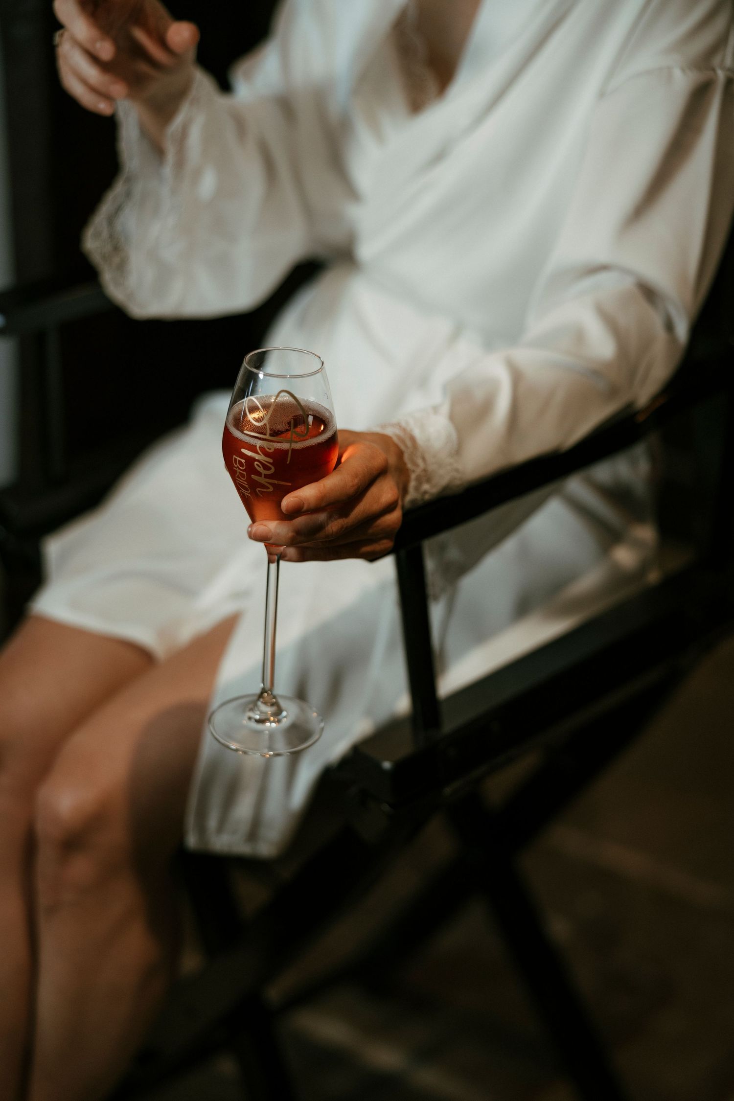 Hand holding a glass of rosé wine in an elegant stemmed glass.