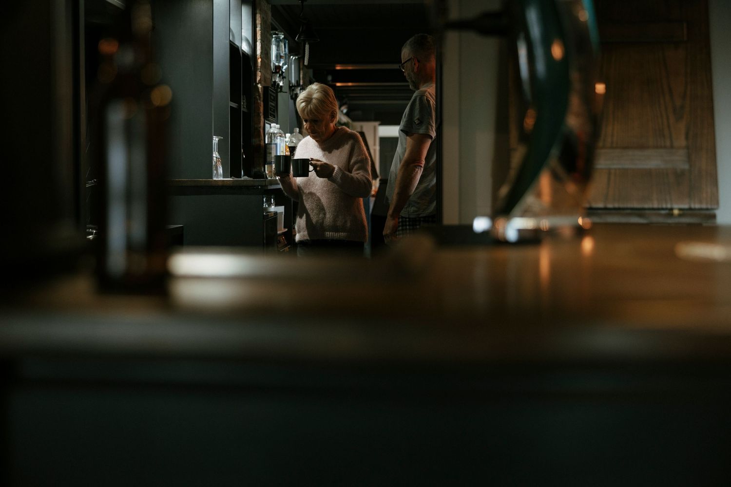 A customer sits at a moody, dimly lit counter in an intimate restaurant interior.