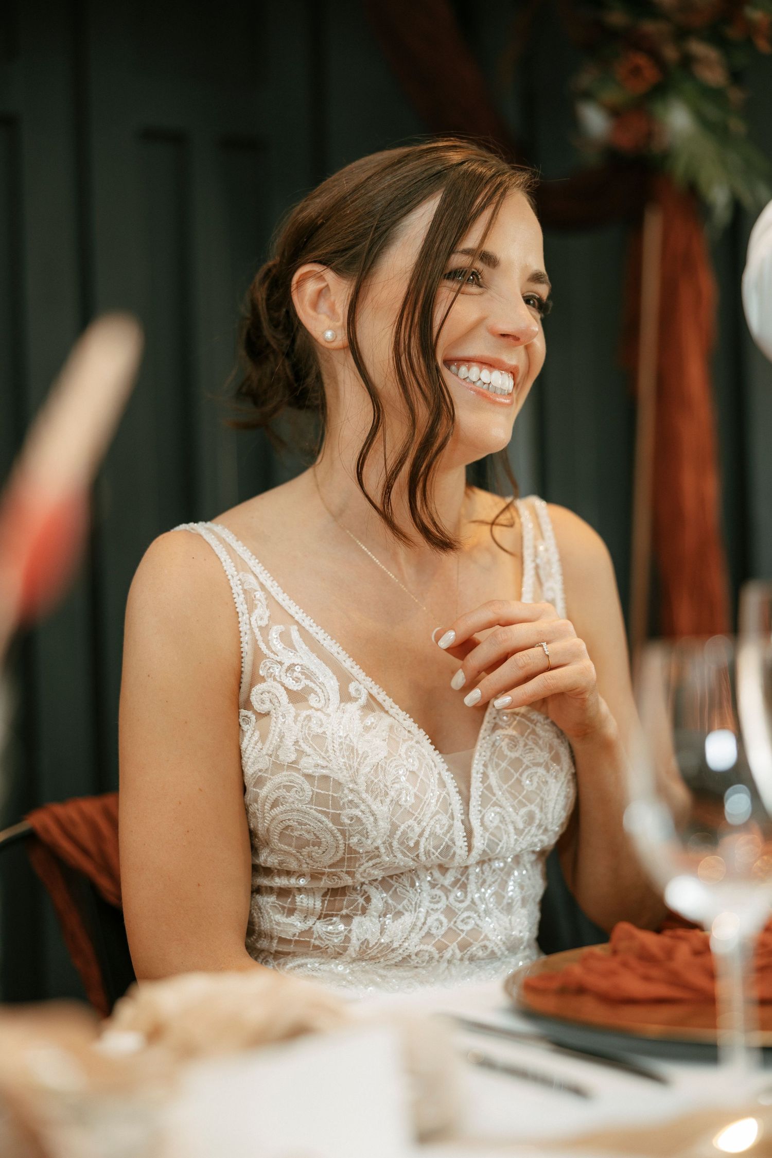 Happy bride in a detailed lace wedding dress laughing during reception.