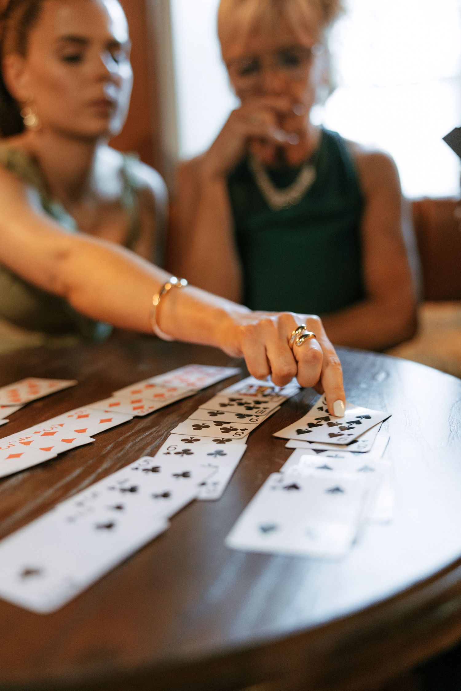 Card game in progress with playing cards laid out on dark wooden table surface.